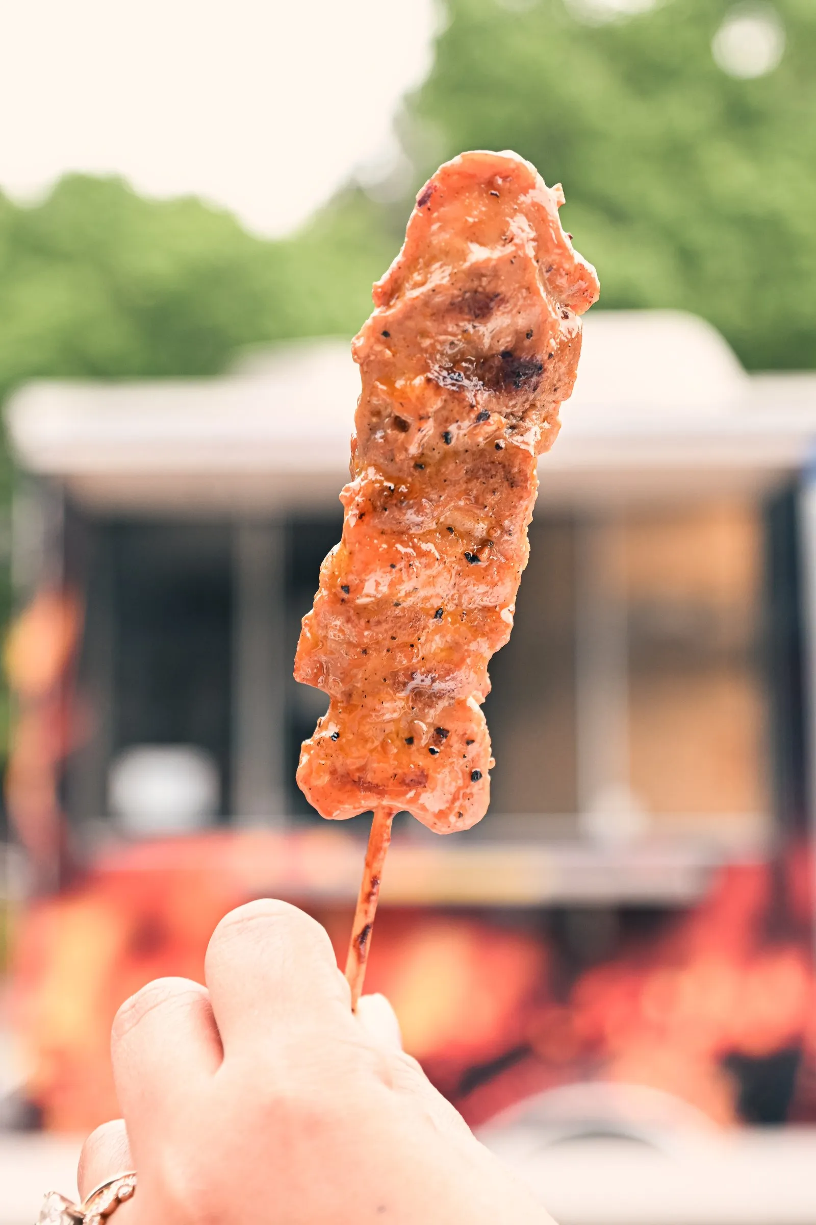 Close view of a glazed barbecue skewer in front of the food truck