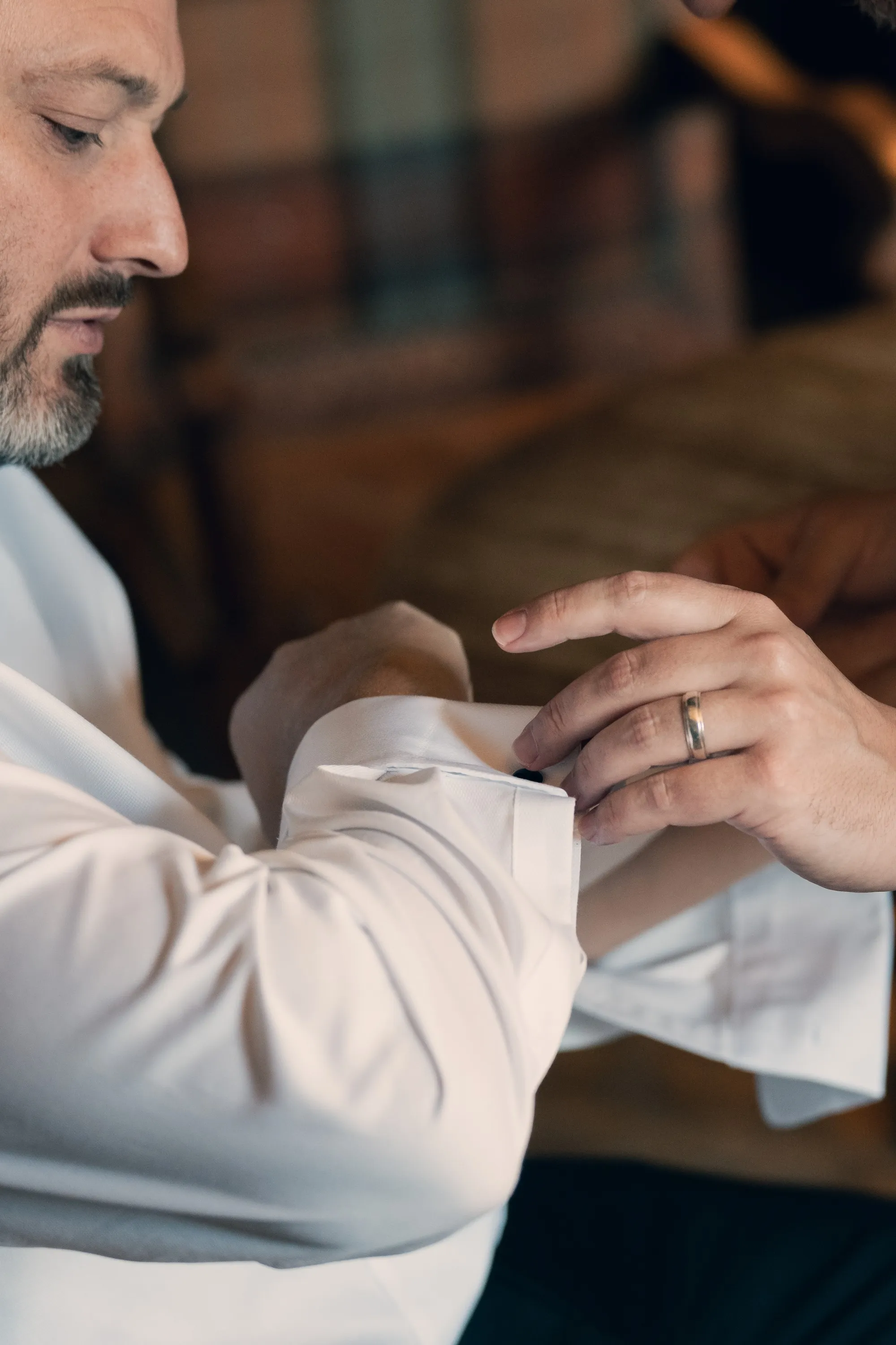 Groom in a white shirt fastening his cuff, wedding band on his finger, Cinema edit