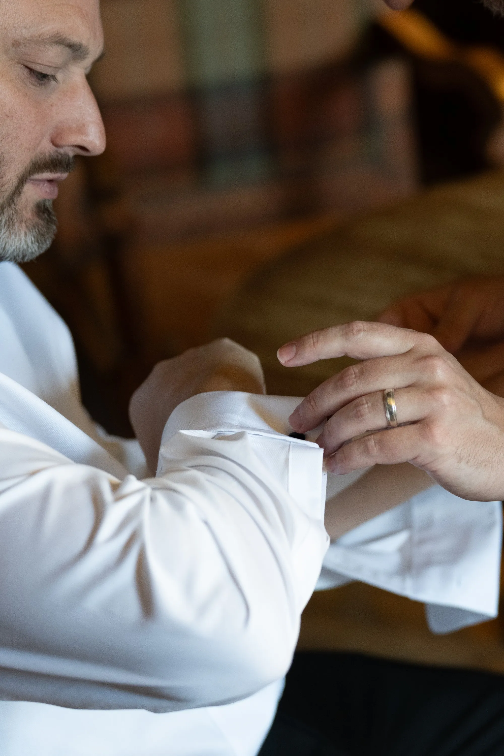 Groom in a white shirt fastening his cuff, wedding band on his finger, Cinema, straight out of the camera before editing