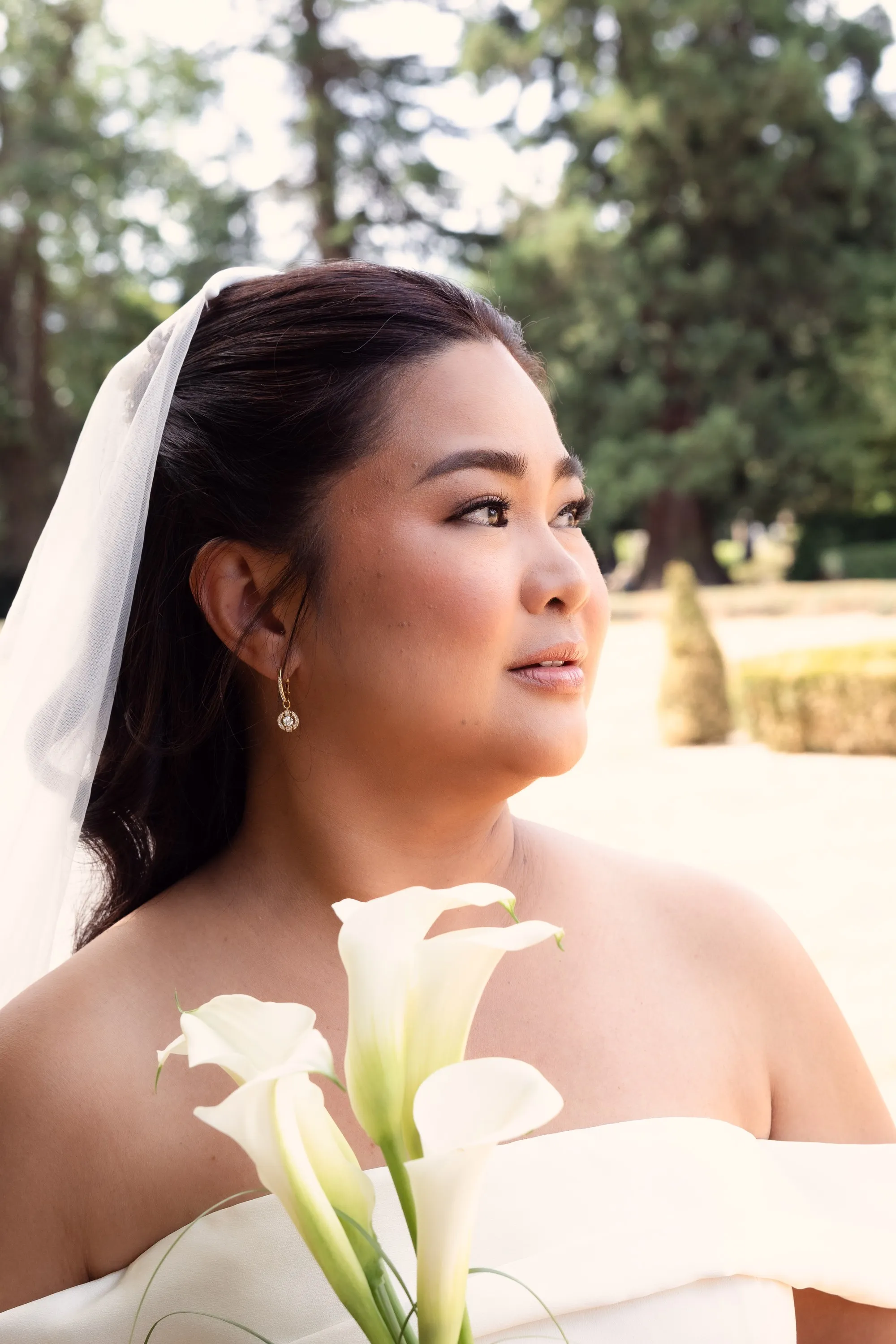 Bridal portrait of a bride in a veil holding white calla lilies, Heirloom edit