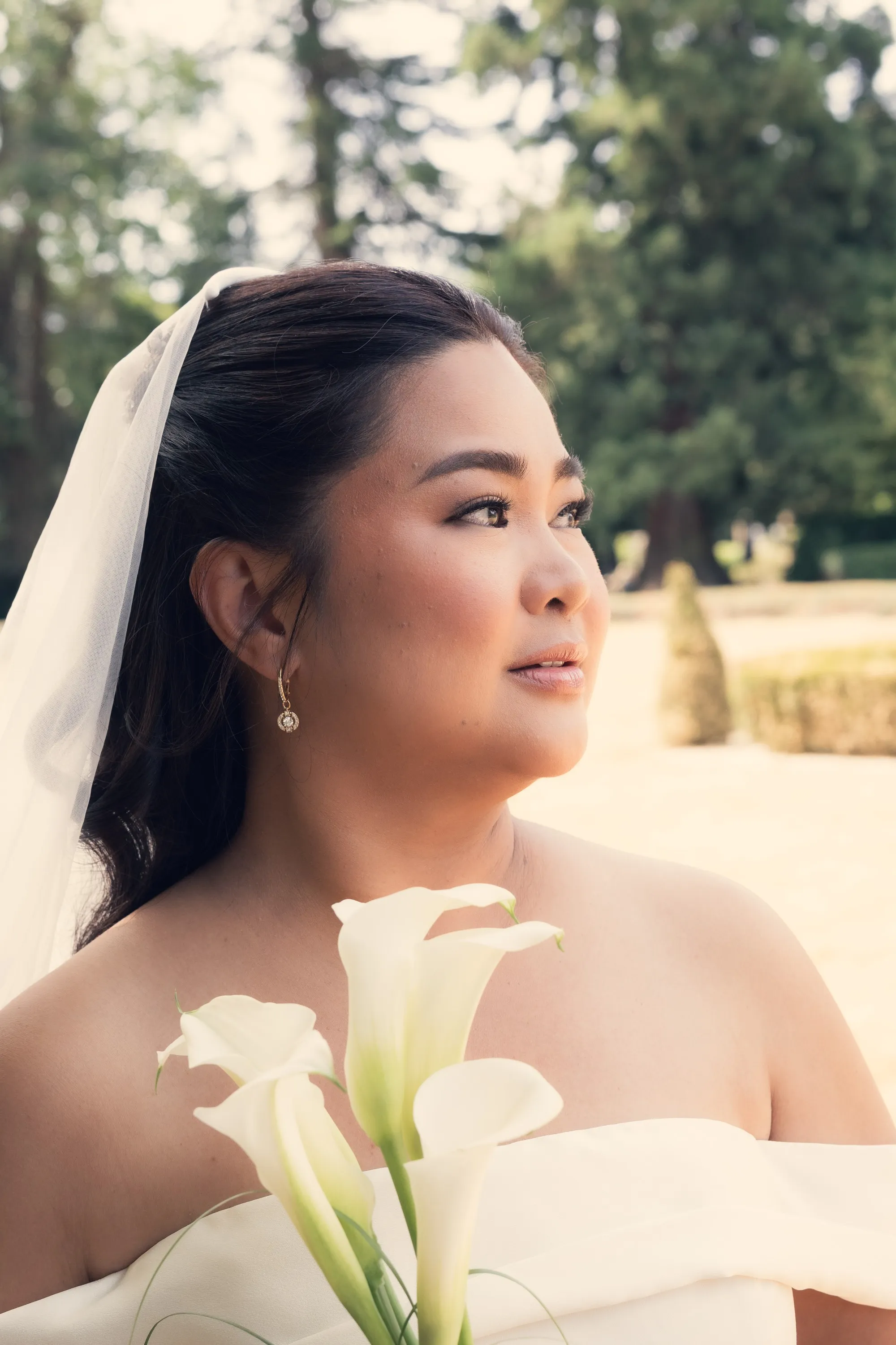 Bridal portrait of a bride in a veil holding white calla lilies, Heirloom Film edit