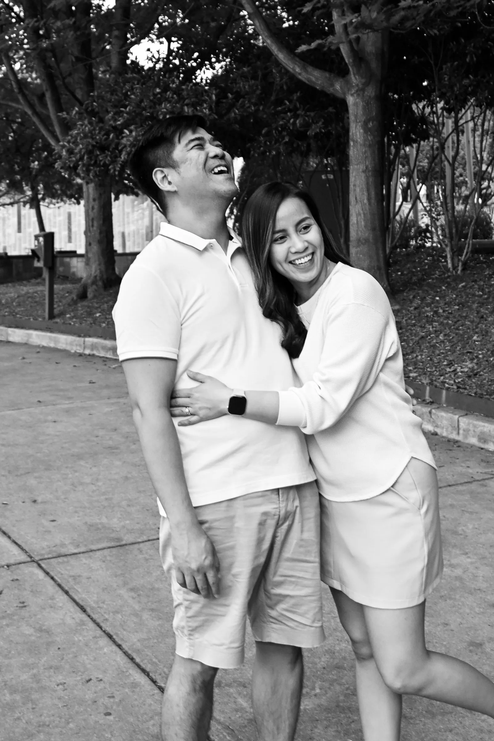Black and white photograph of Jet laughing as Jessica leans into him