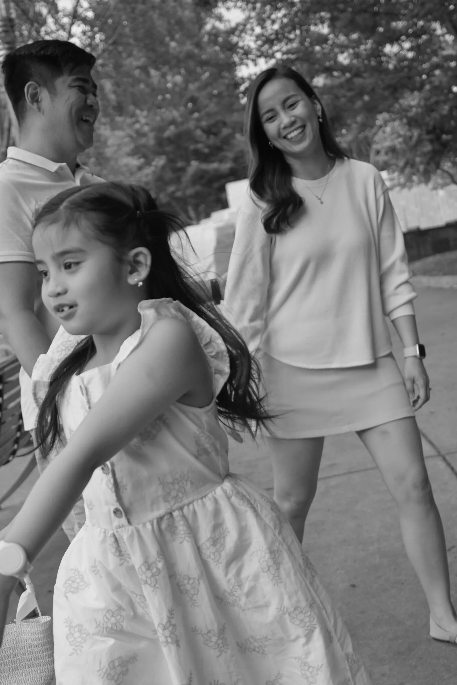 Black and white photograph of their daughter swinging her dress as Jessica and Jet watch