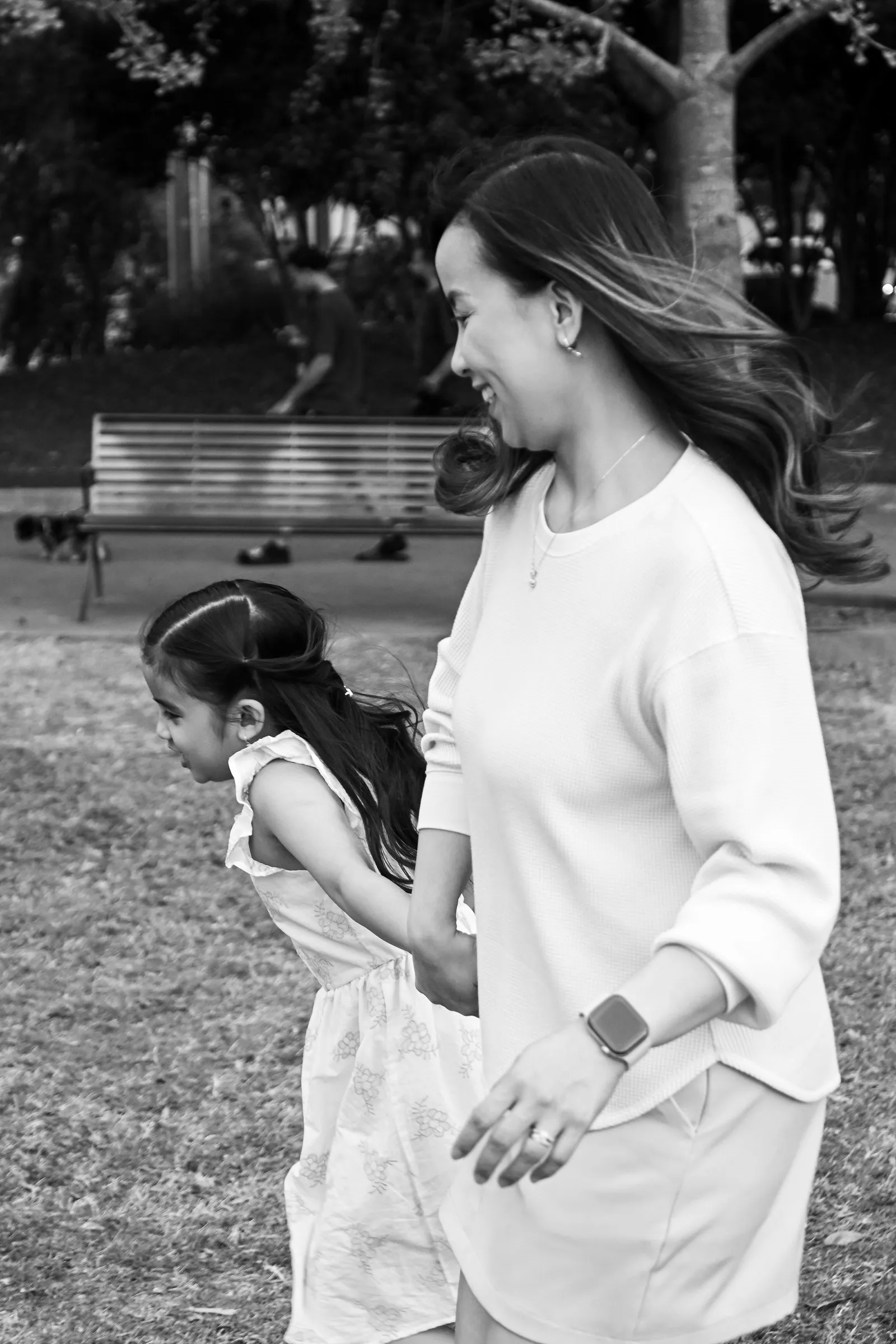 Black and white photograph of Jessica walking hand in hand with her daughter across the lawn