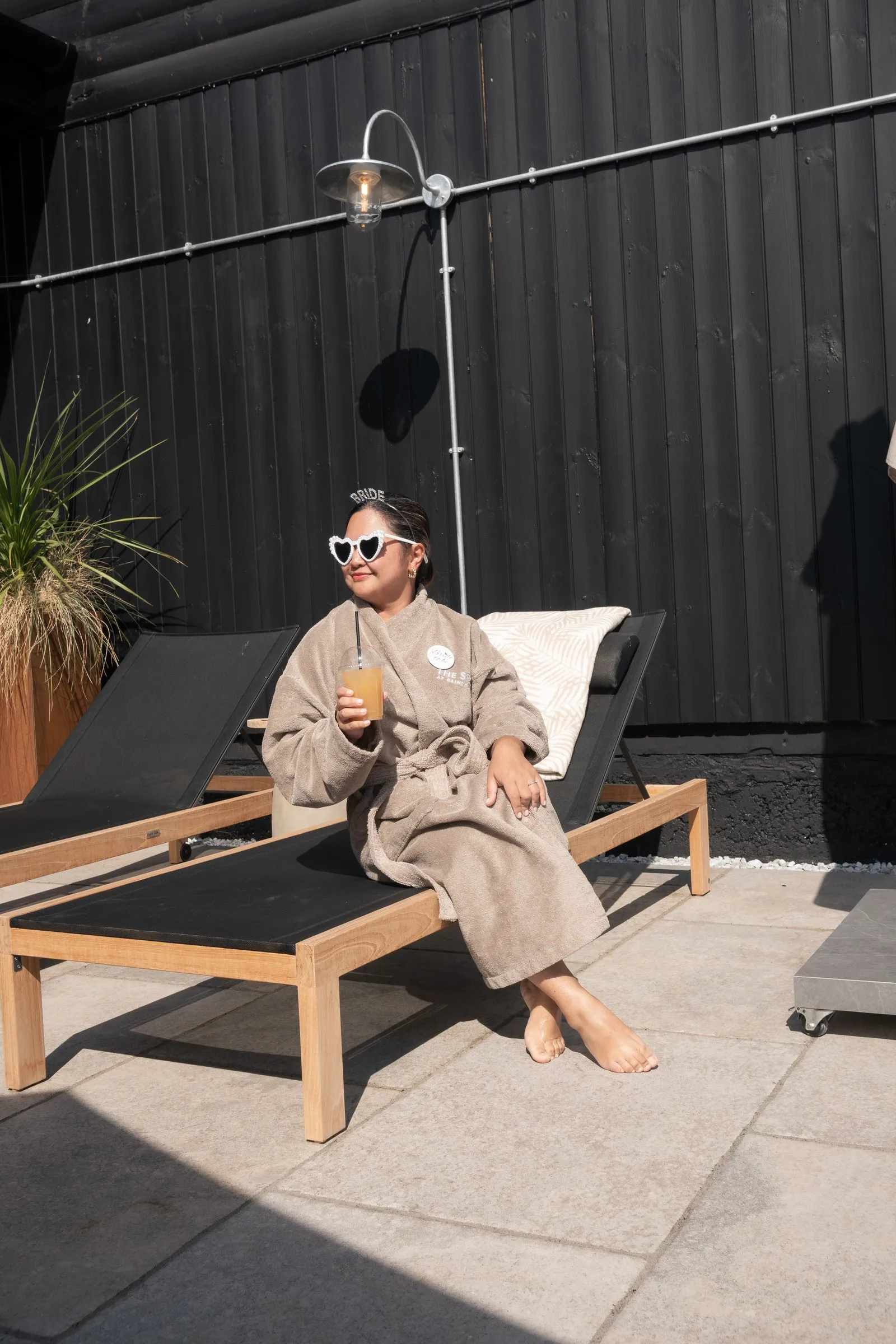 A guest in heart sunglasses lounging in the sun in a plush robe