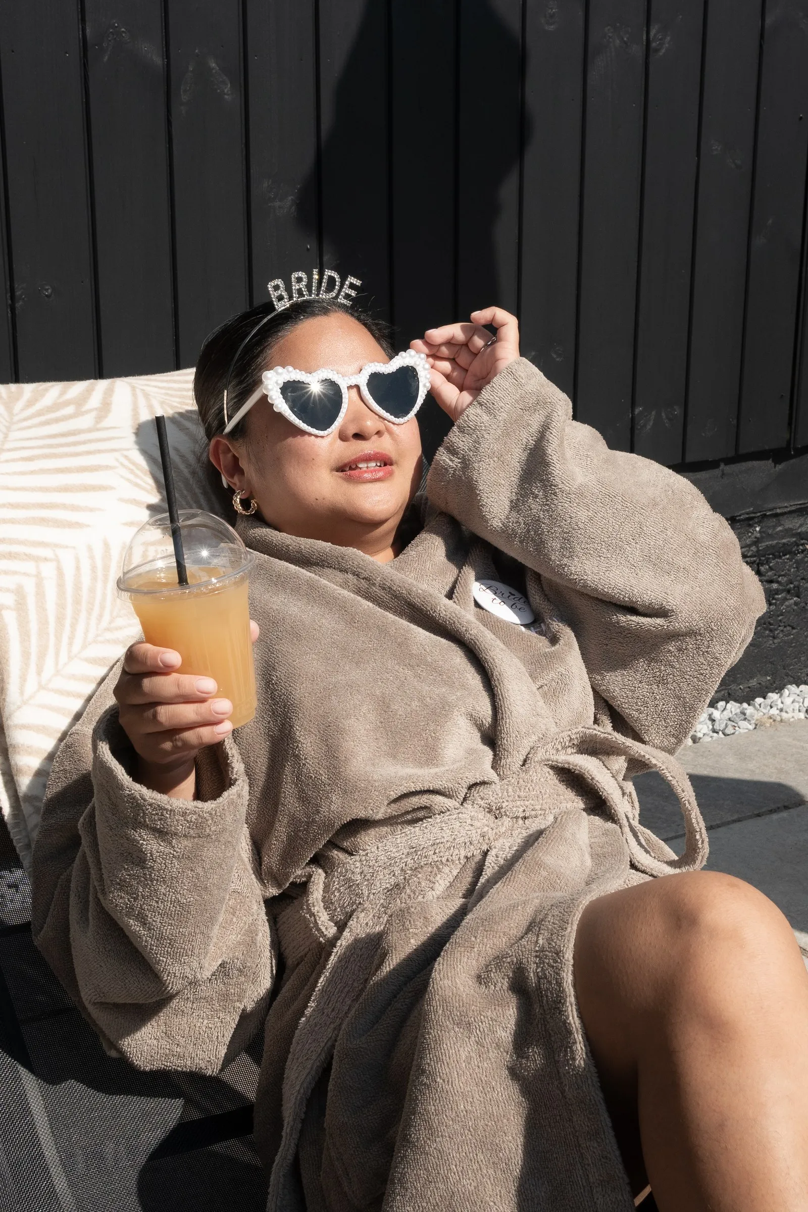Mathelle adjusting her heart sunglasses with a cocktail in hand