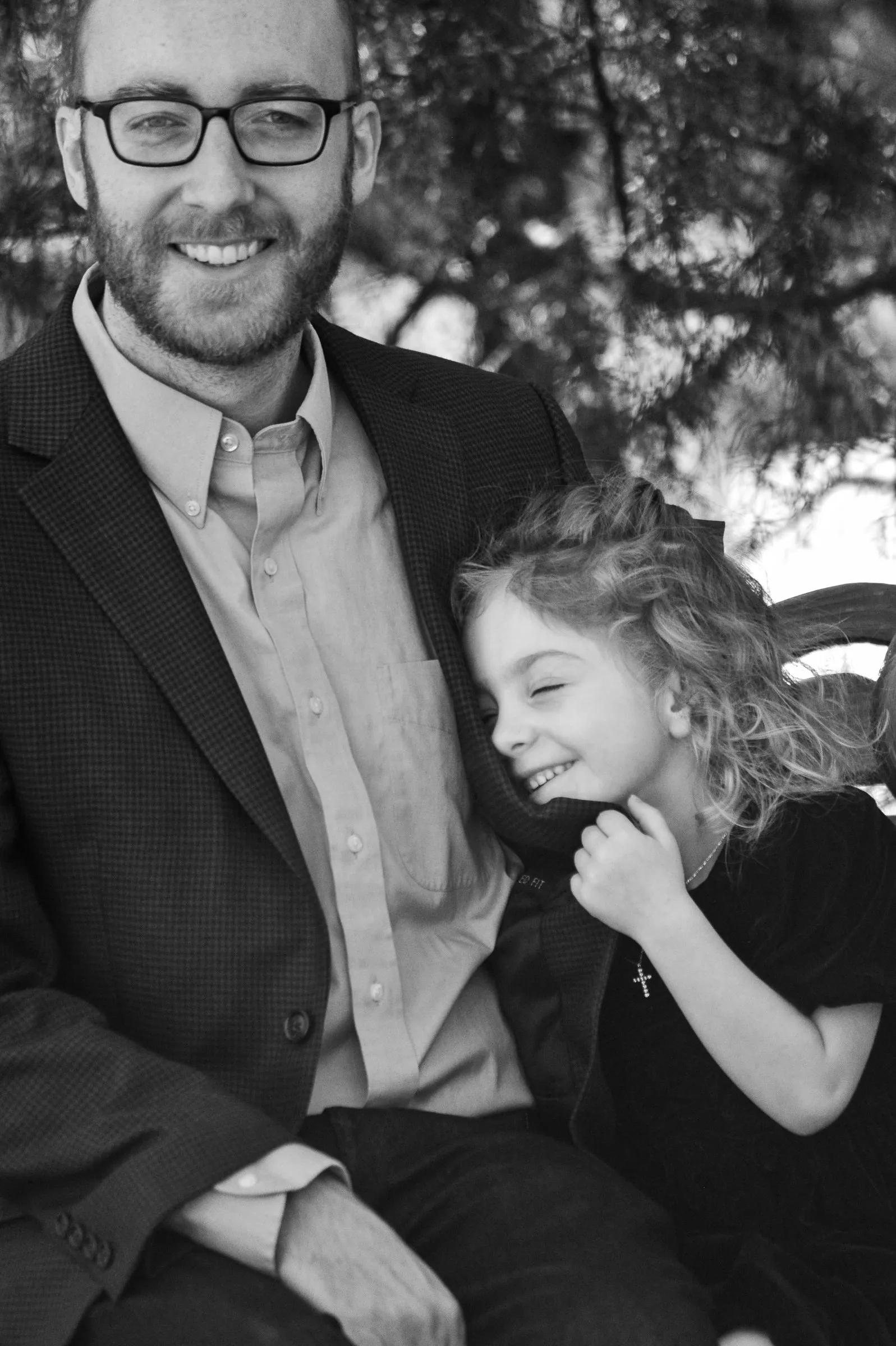 Black and white photograph of Olivia's daughter laughing as she snuggles into Matt's blazer at Marvin Efird Park in Waxhaw, NC