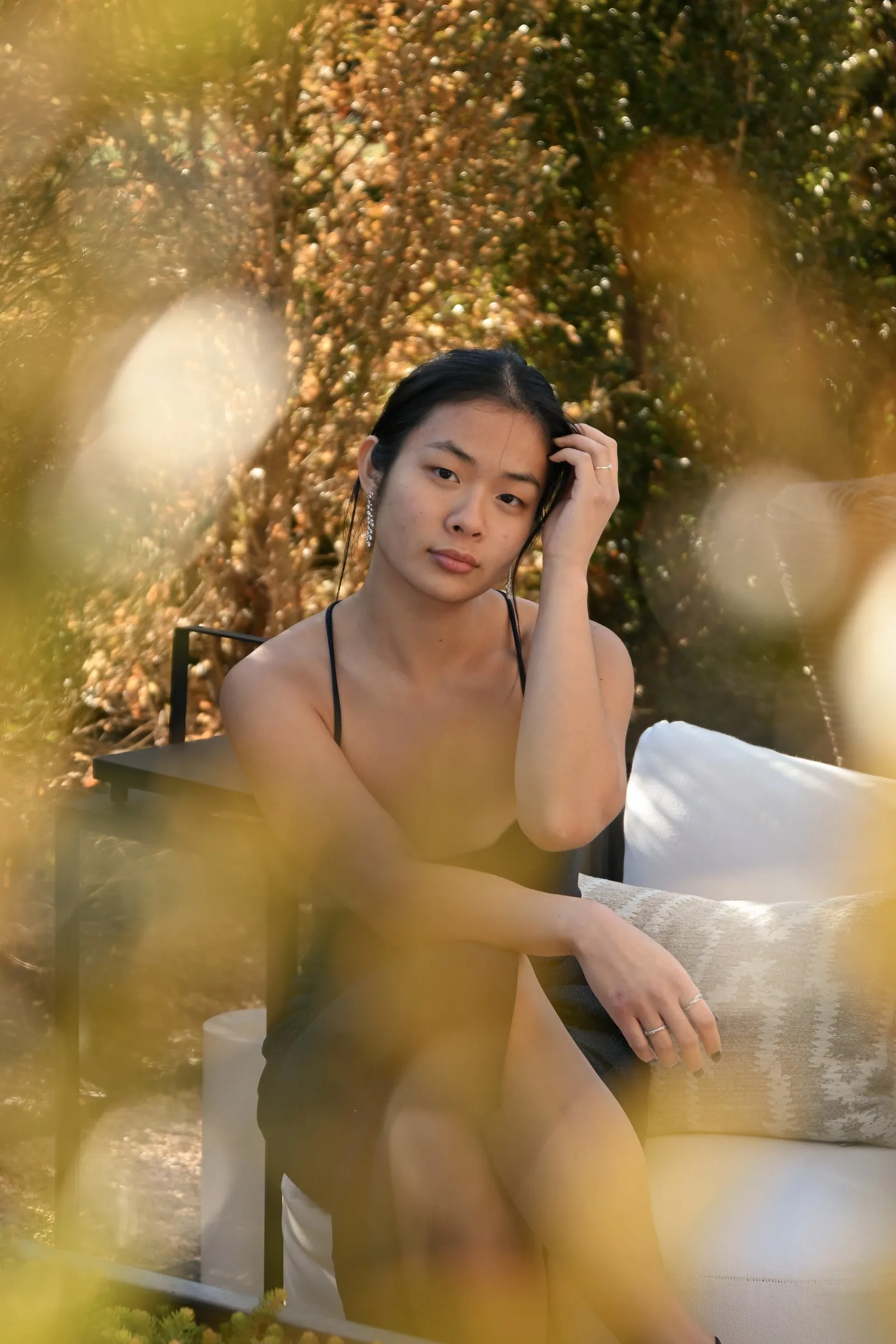 Meilin seated on an outdoor sofa, framed through out of focus golden foliage in warm afternoon light