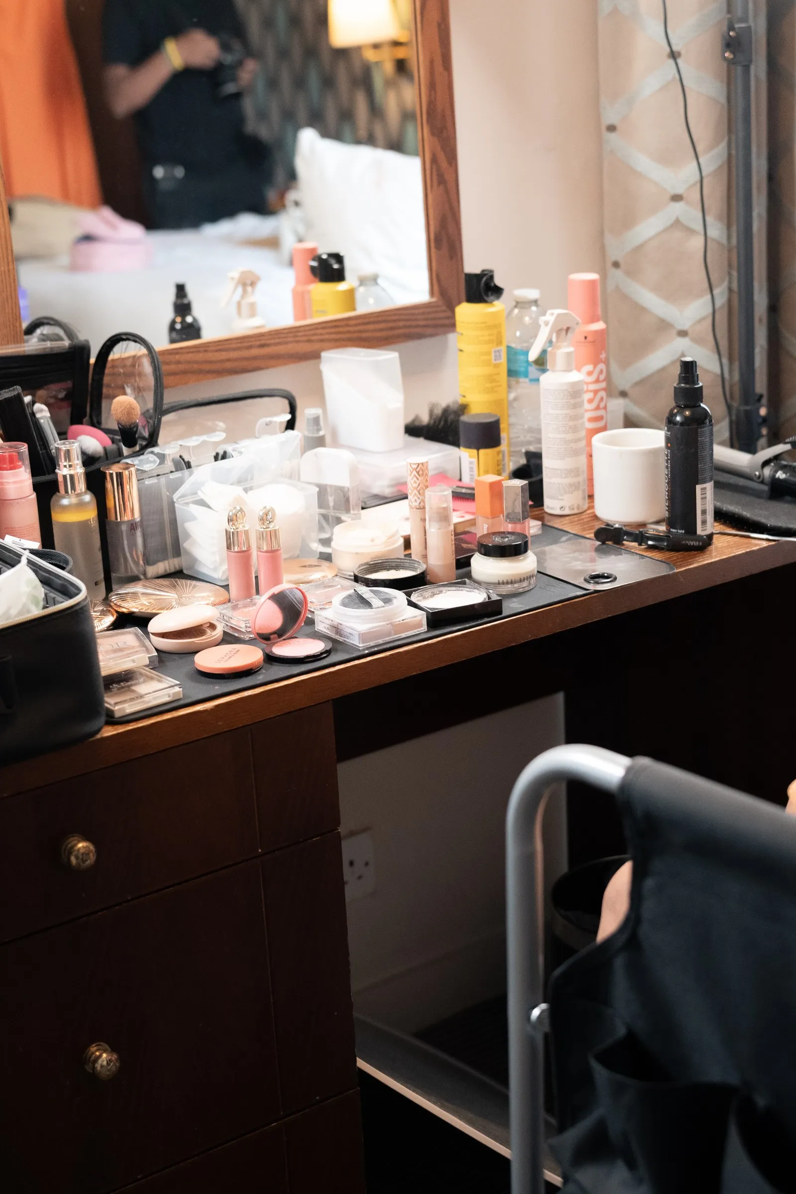Bridal suite dresser covered in makeup and brushes on the wedding morning