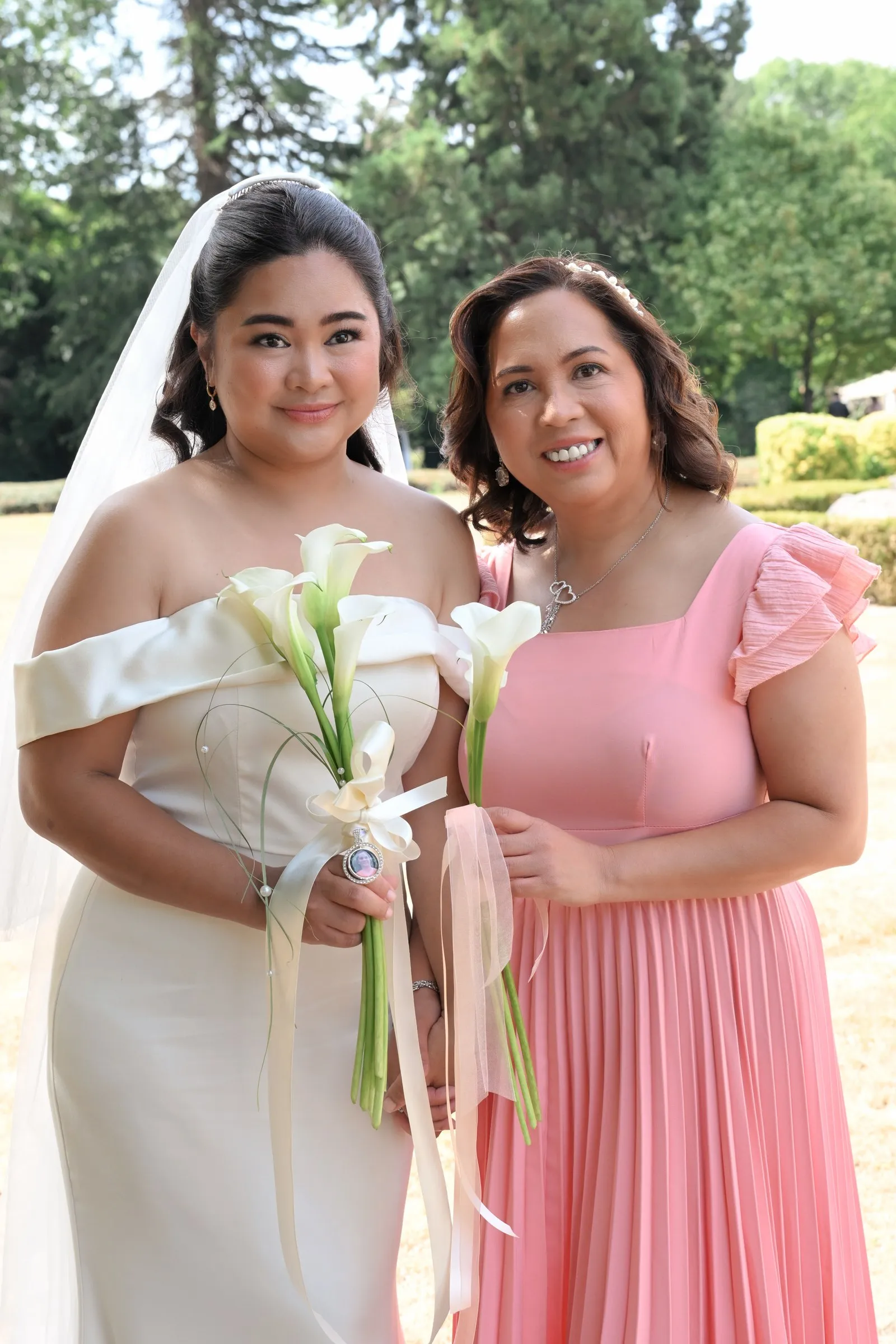 Mathelle with a guest in pink, both holding calla lilies