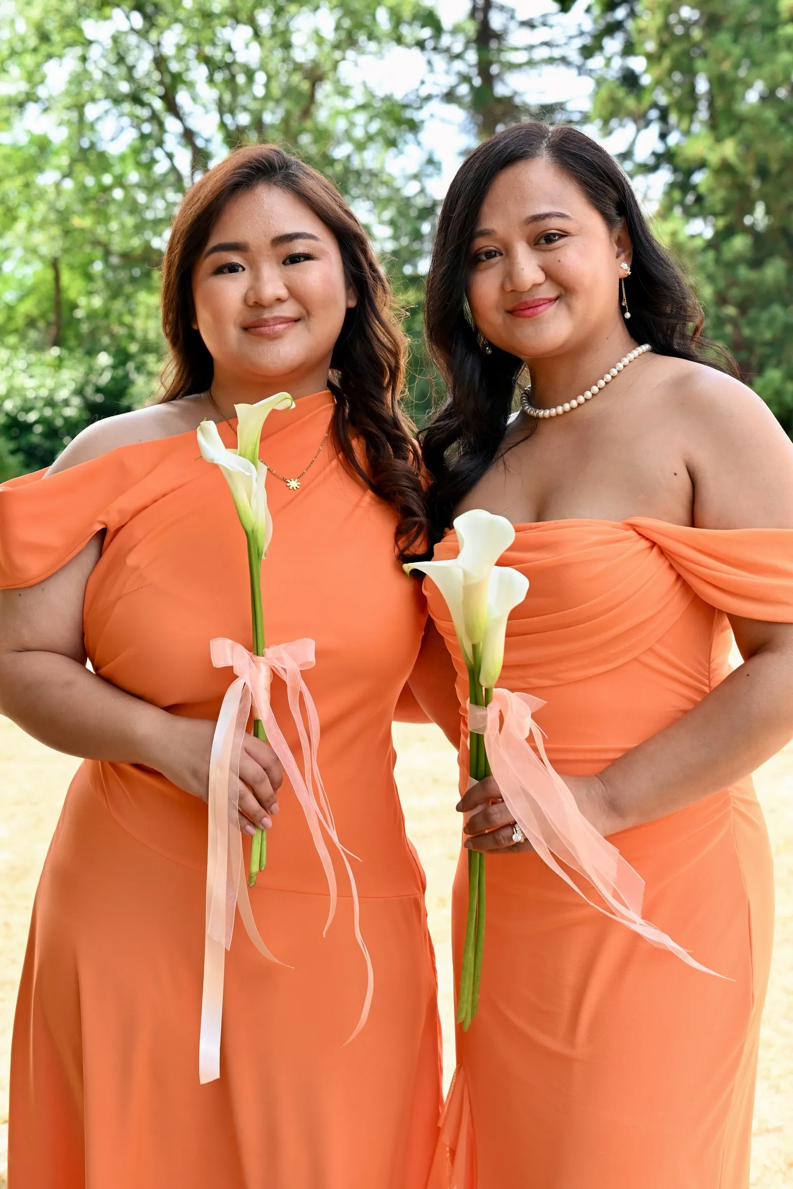 Two bridesmaids in peach dresses holding calla lilies