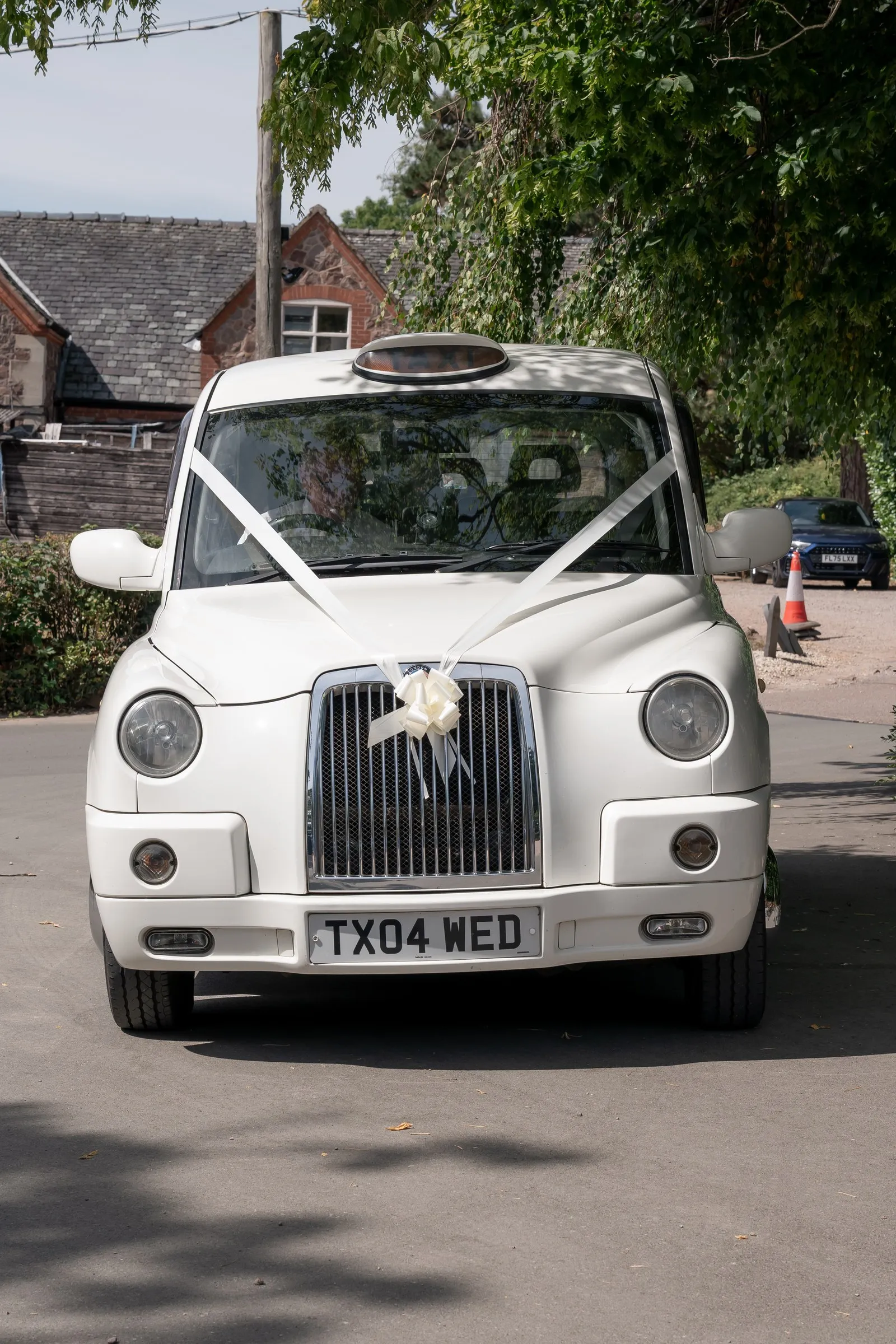 Front view of the white wedding taxi with ribbon on the bonnet