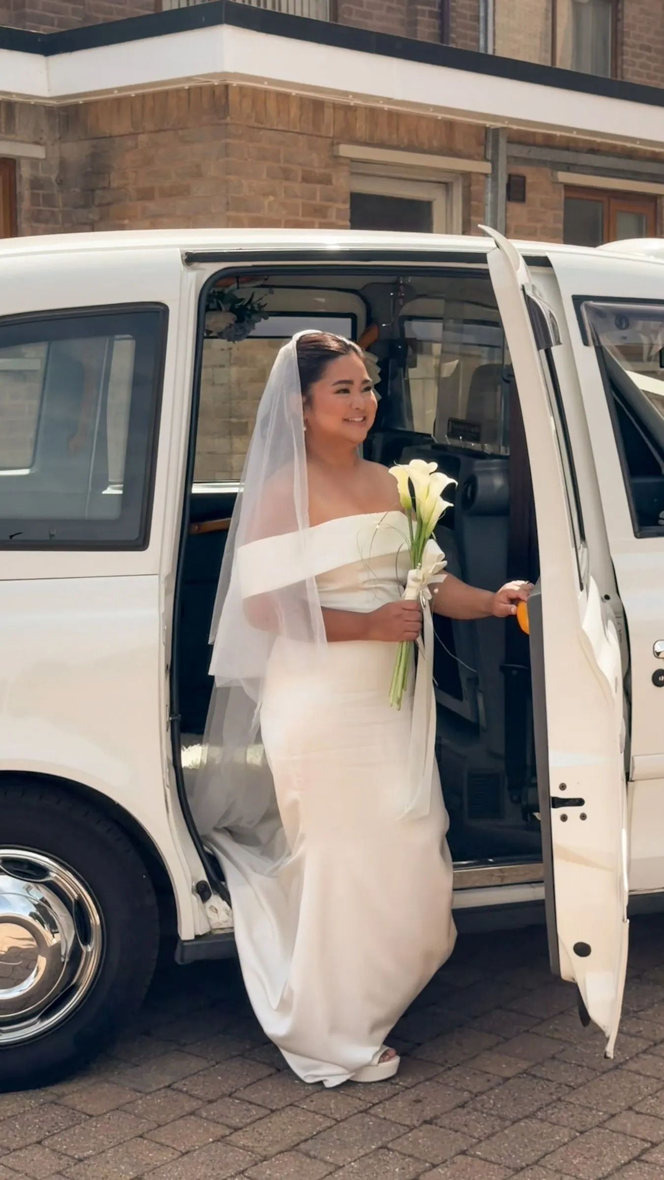 Mathelle stepping out of the white taxi with her bouquet