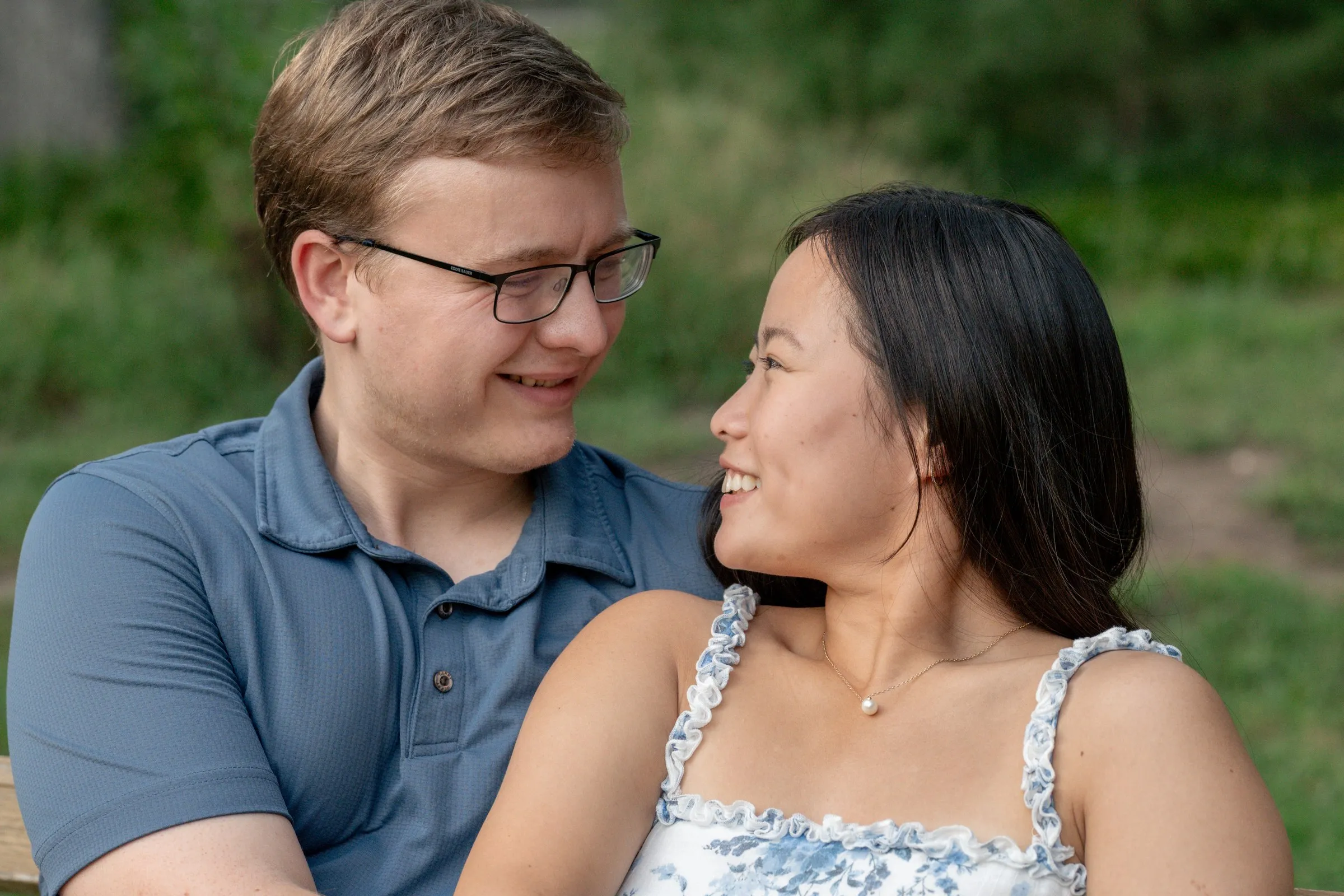 Mya and Jacob smiling at each other while seated on the grass