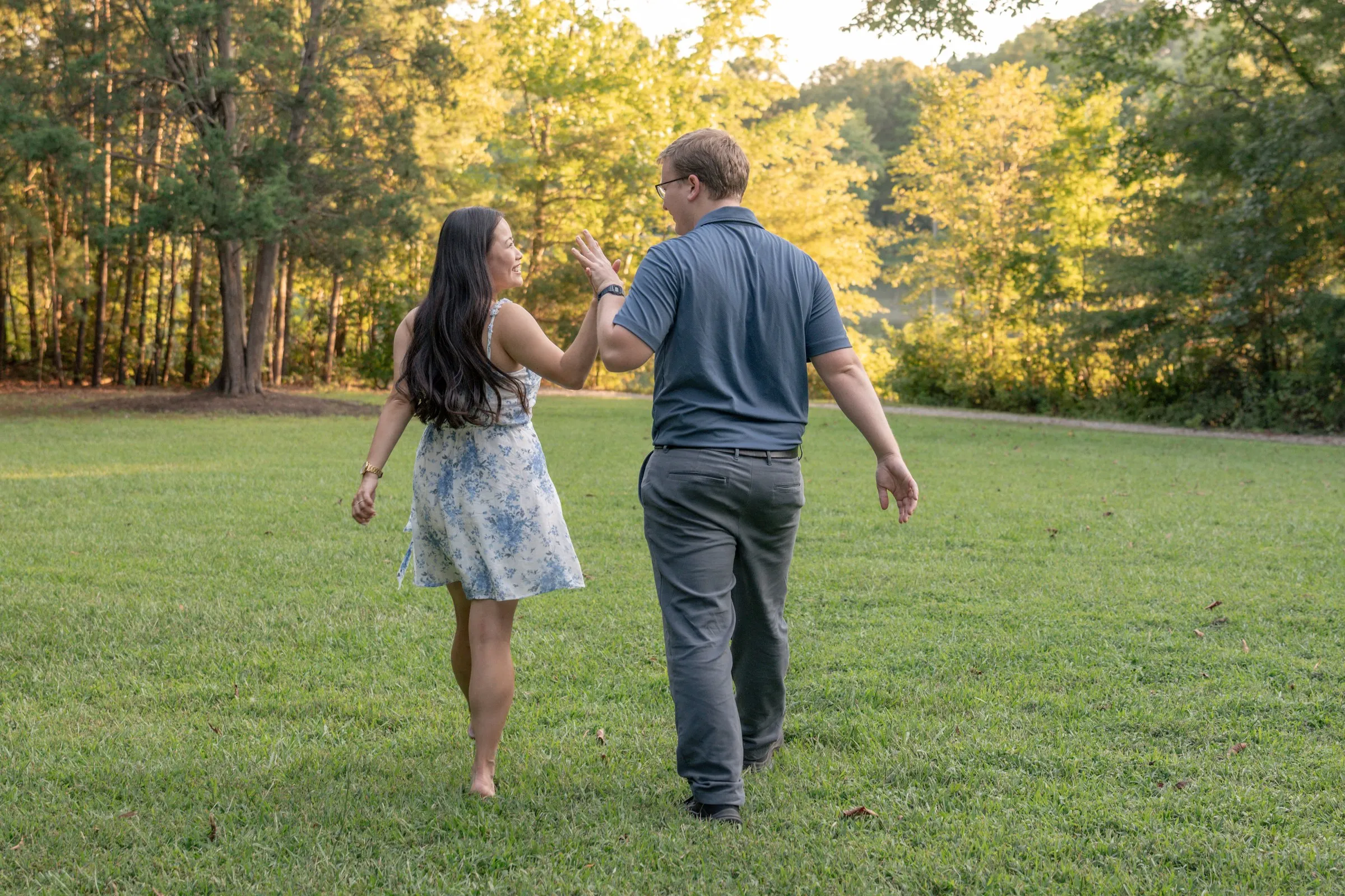 Mya and Jacob walking hand in hand across the lawn at Marvin Efird Park