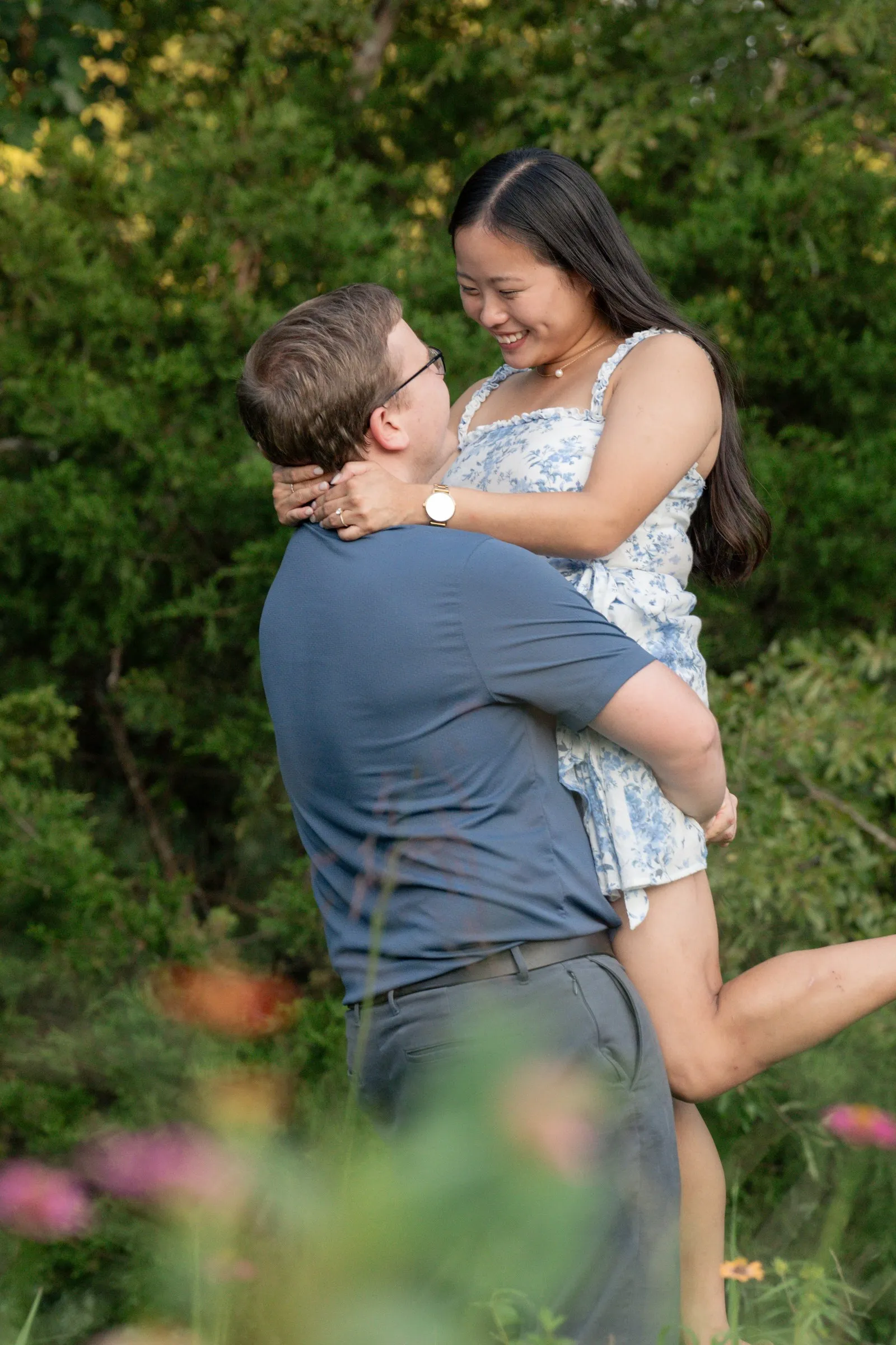 Jacob lifting Mya off the ground as she laughs in the wildflower field