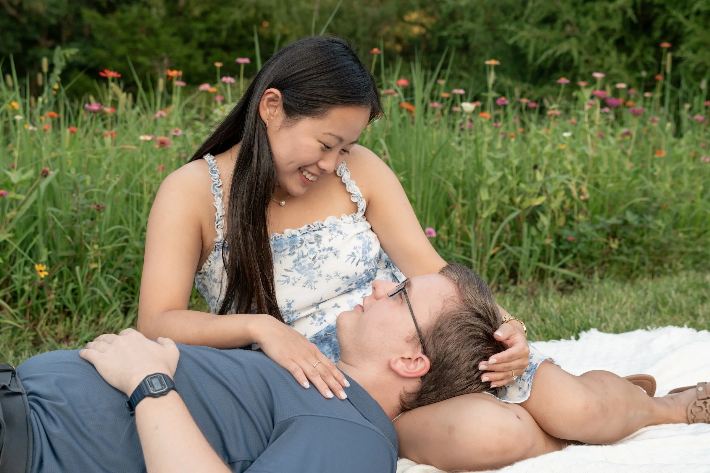 Mya sitting on the blanket with Jacob's head in her lap, wildflowers behind them
