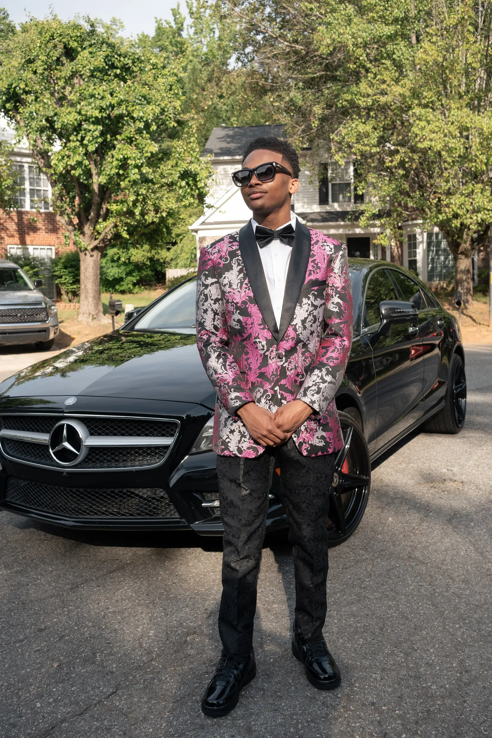 Hands clasped in front of the black Mercedes