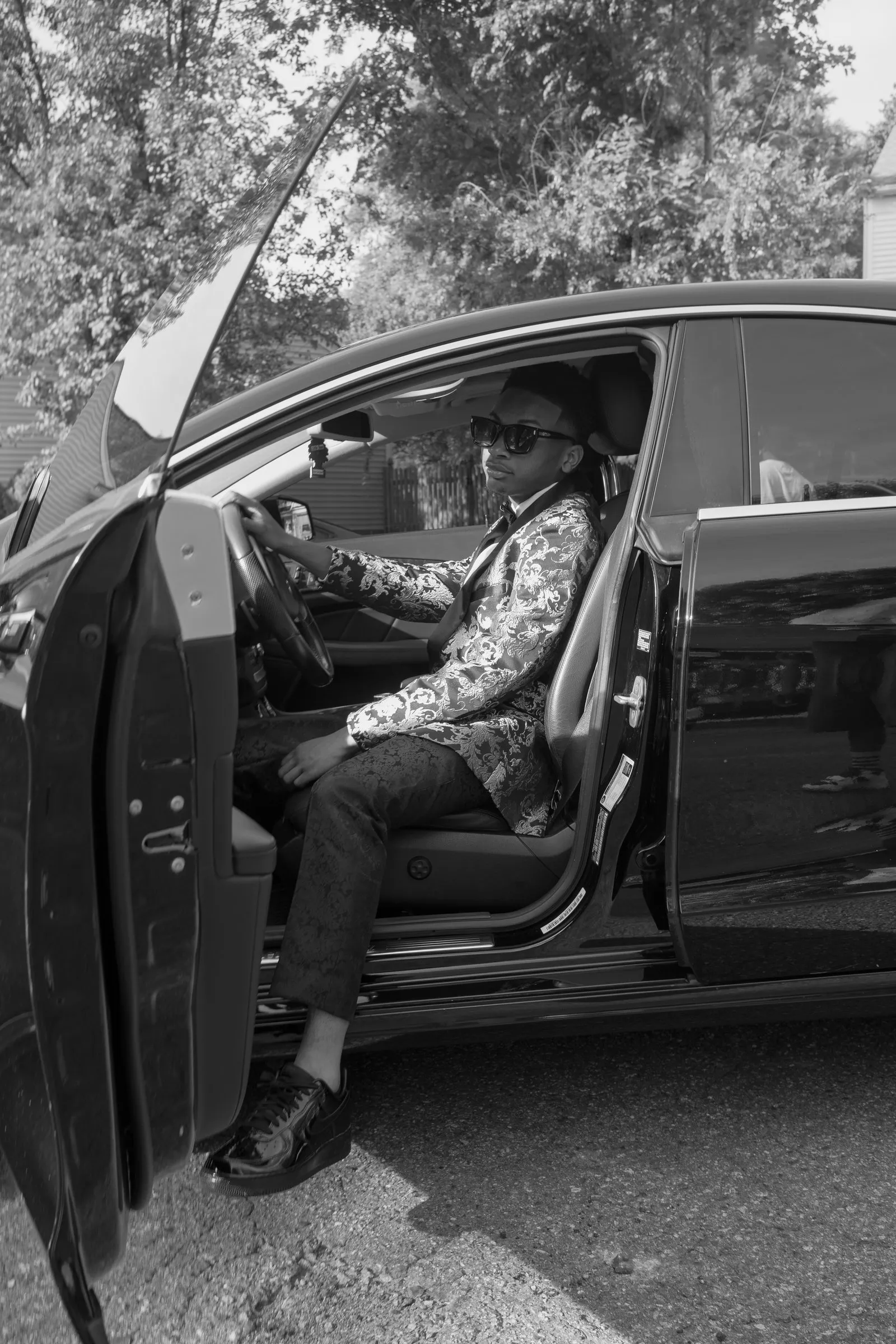 Black and white photograph of him in the driver's seat with the door open
