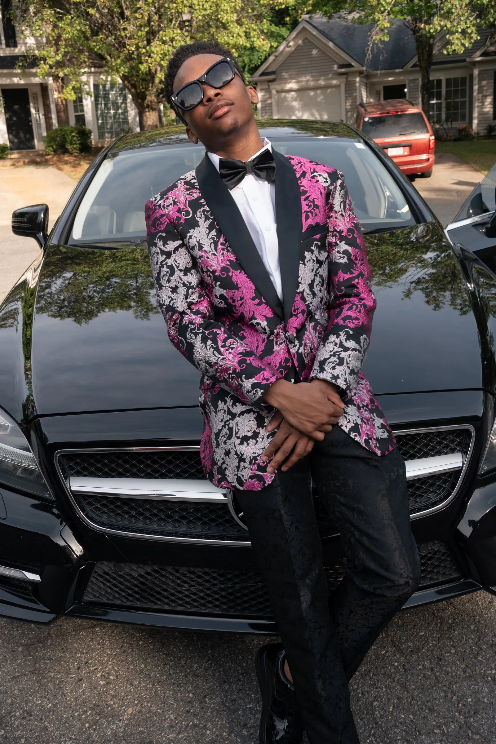 He leans back on the hood of the black Mercedes
