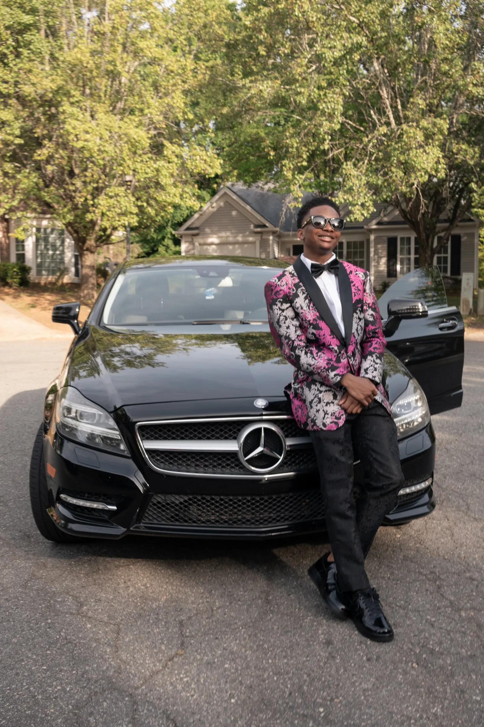 He sits on the front of the Mercedes, the door open behind him
