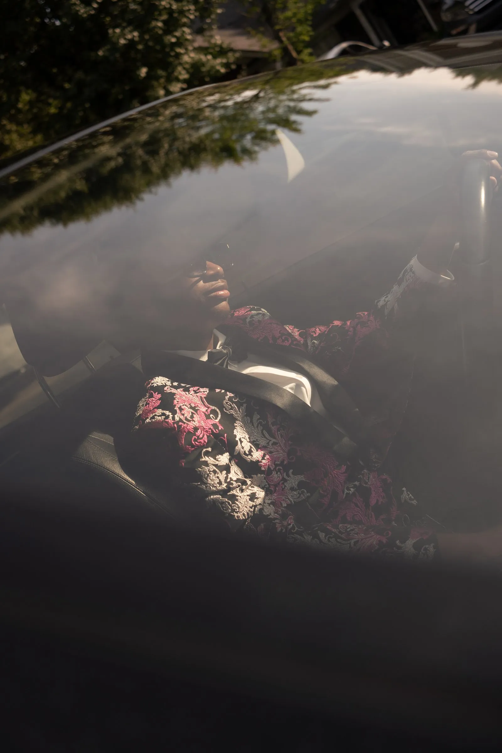 His reflection in the car's dark glass