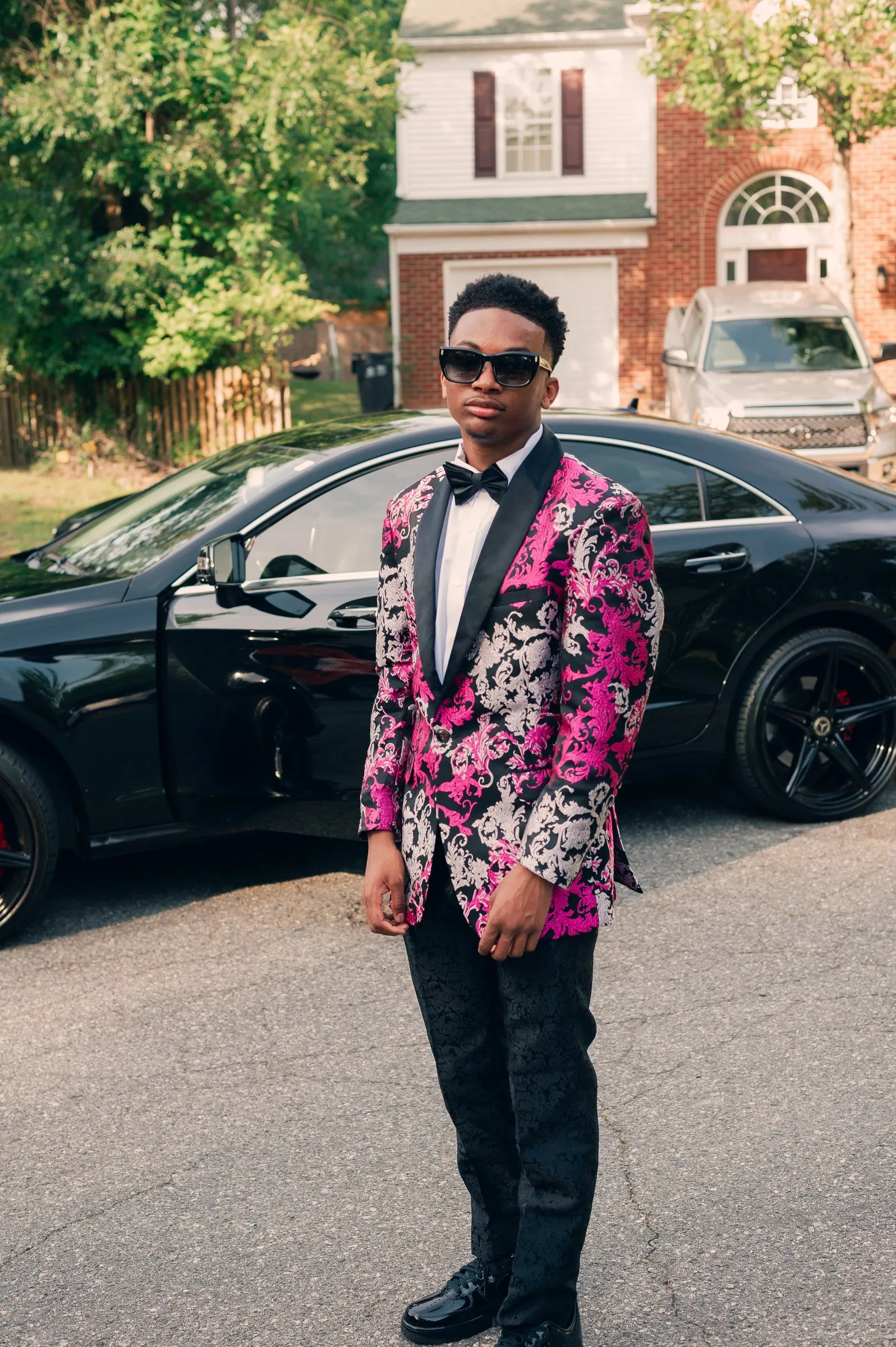Full length prom portrait in the street beside a black car