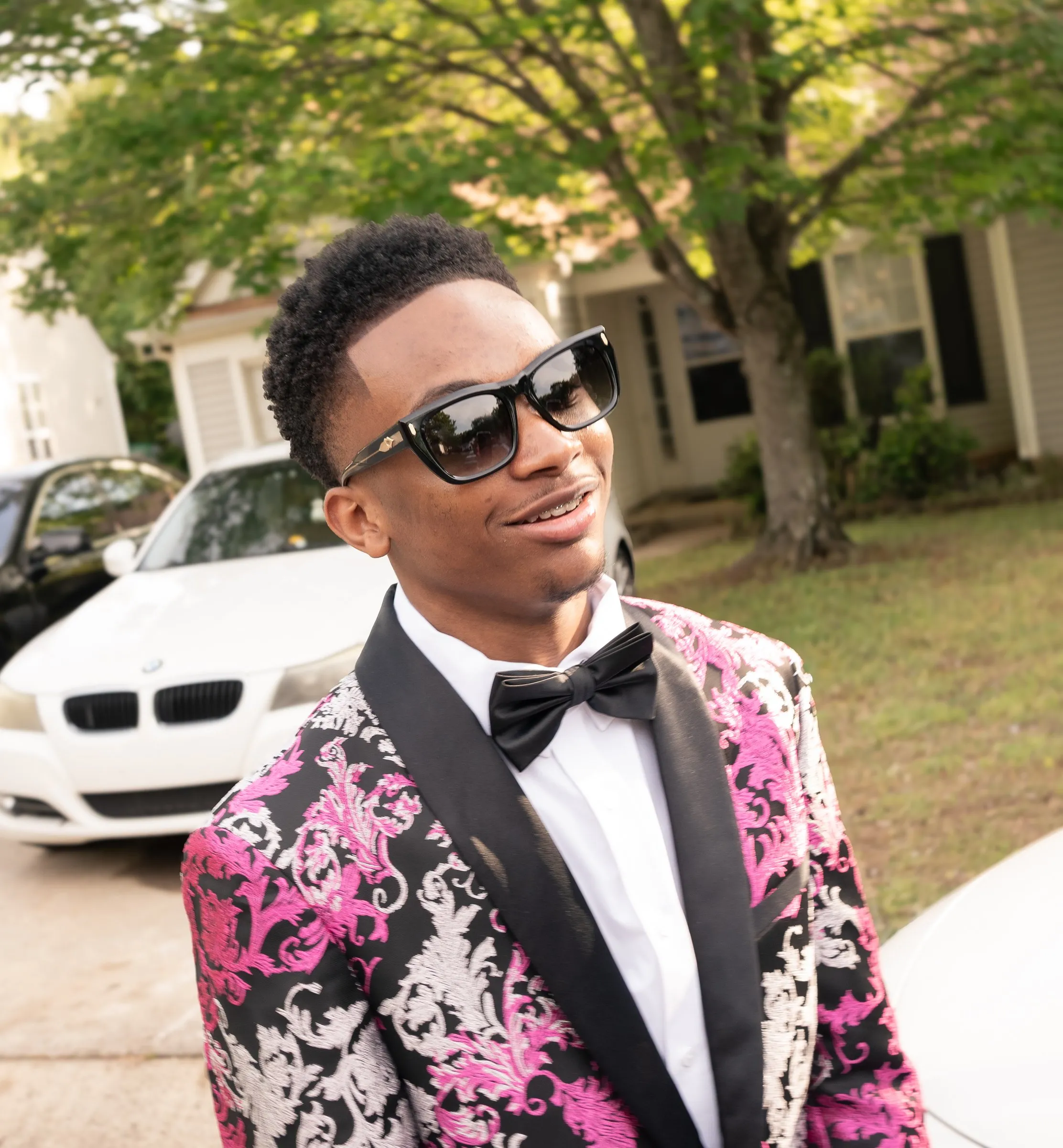He looks up and smiles in sunglasses under the trees