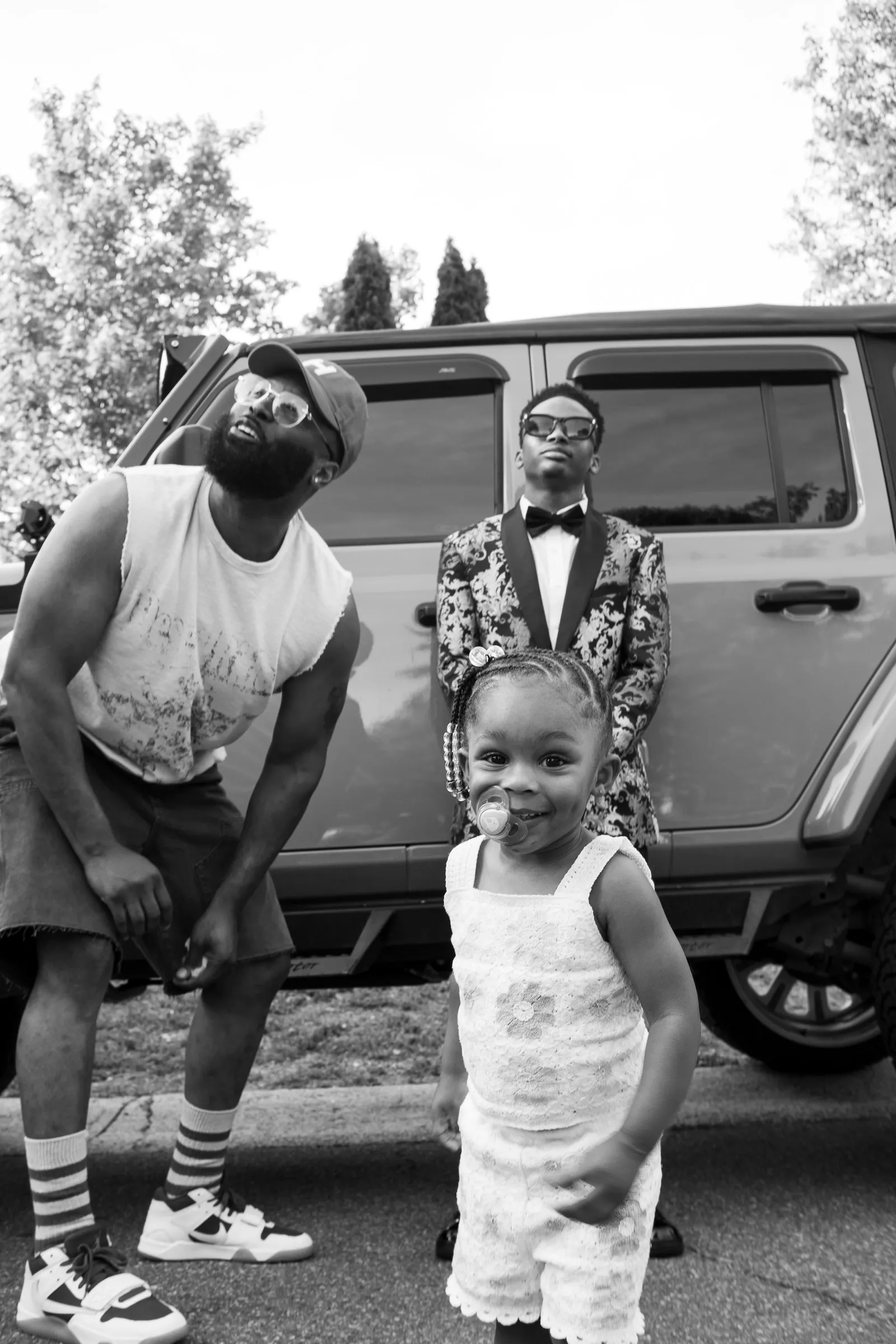 Black and white photograph of a little girl posing in front of the Jeep with them