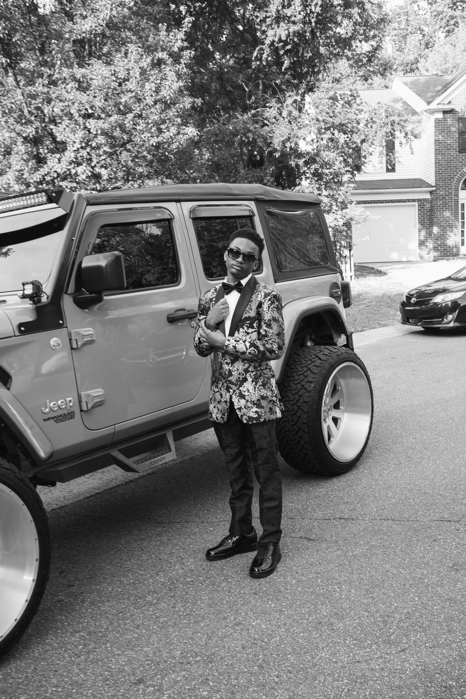 Black and white photograph of him beside the lifted Jeep