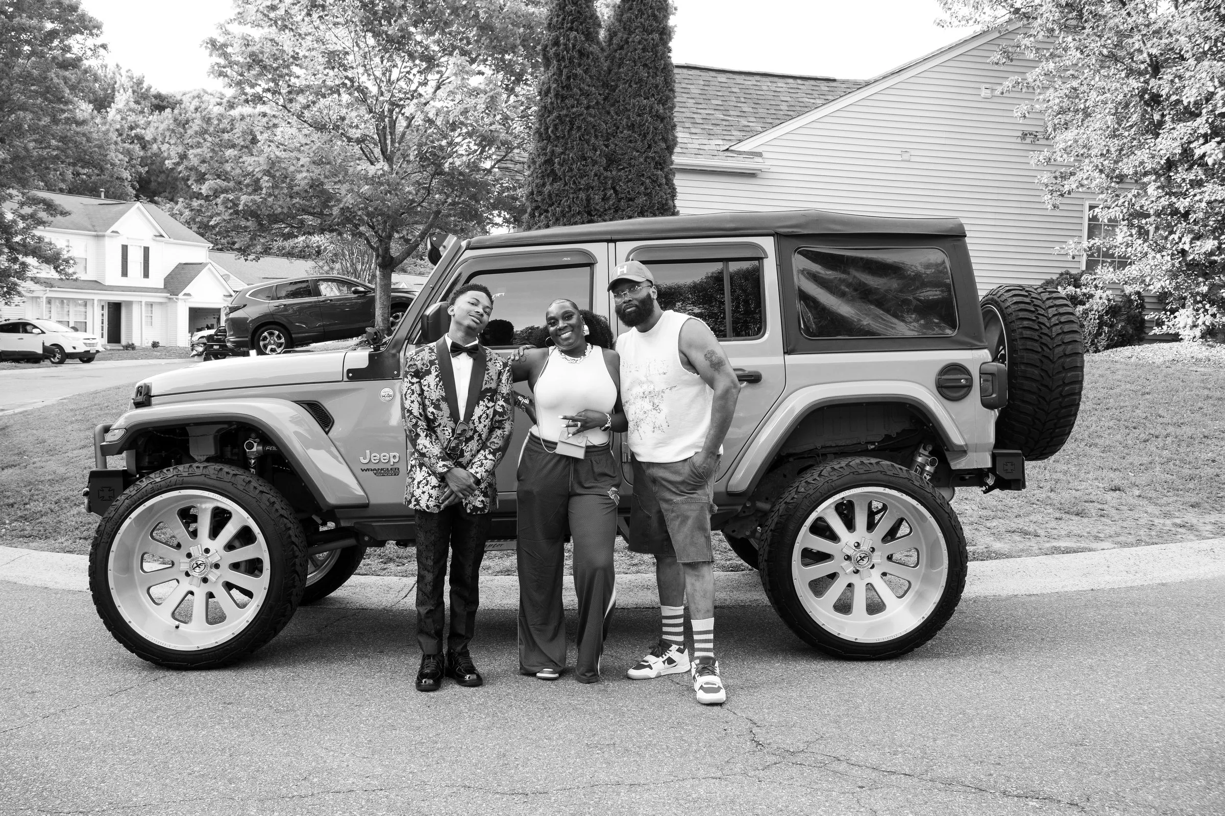 Black and white photograph of three across in front of the Jeep