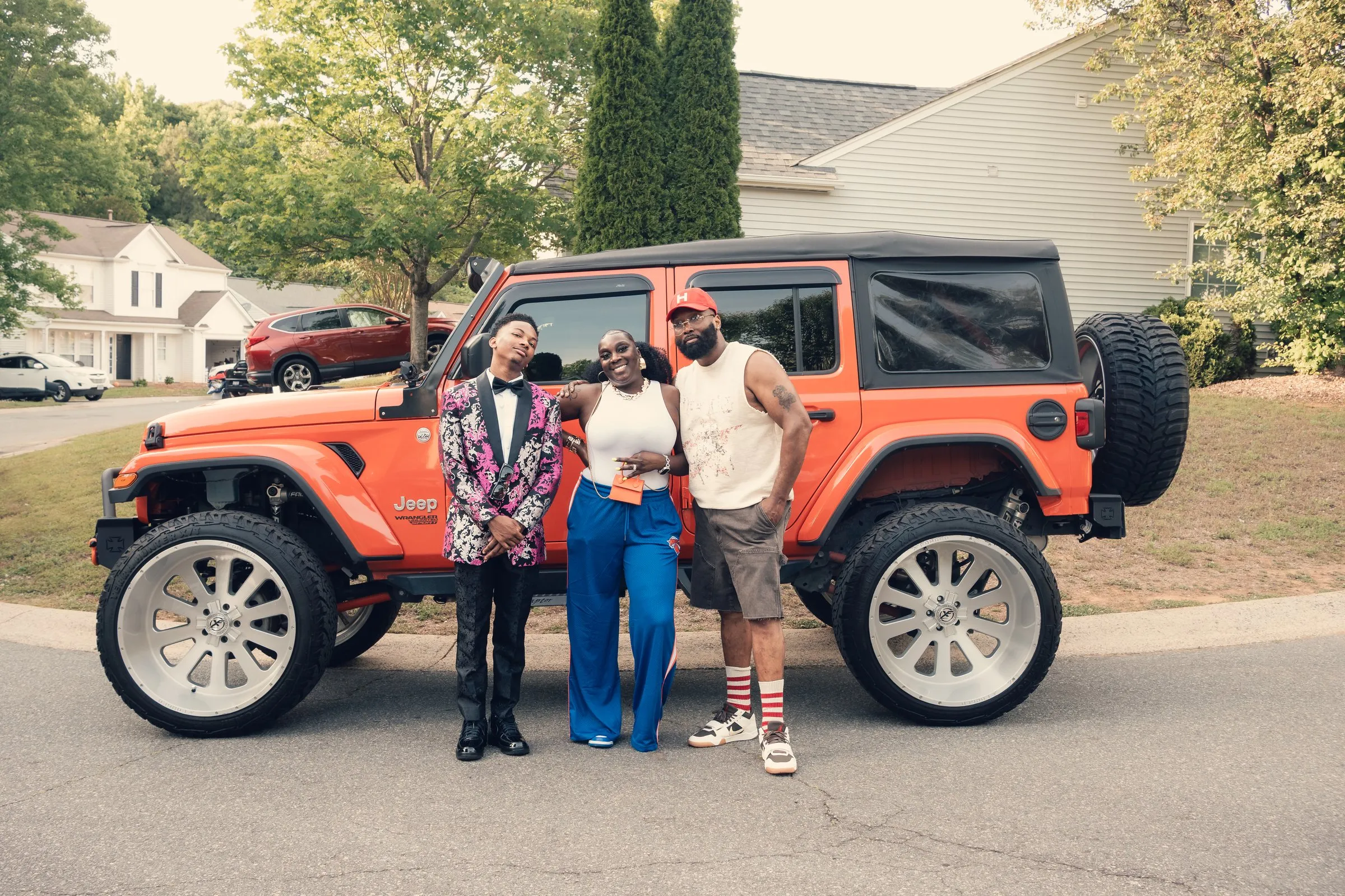 Wide family photograph in front of the orange Jeep Wrangler