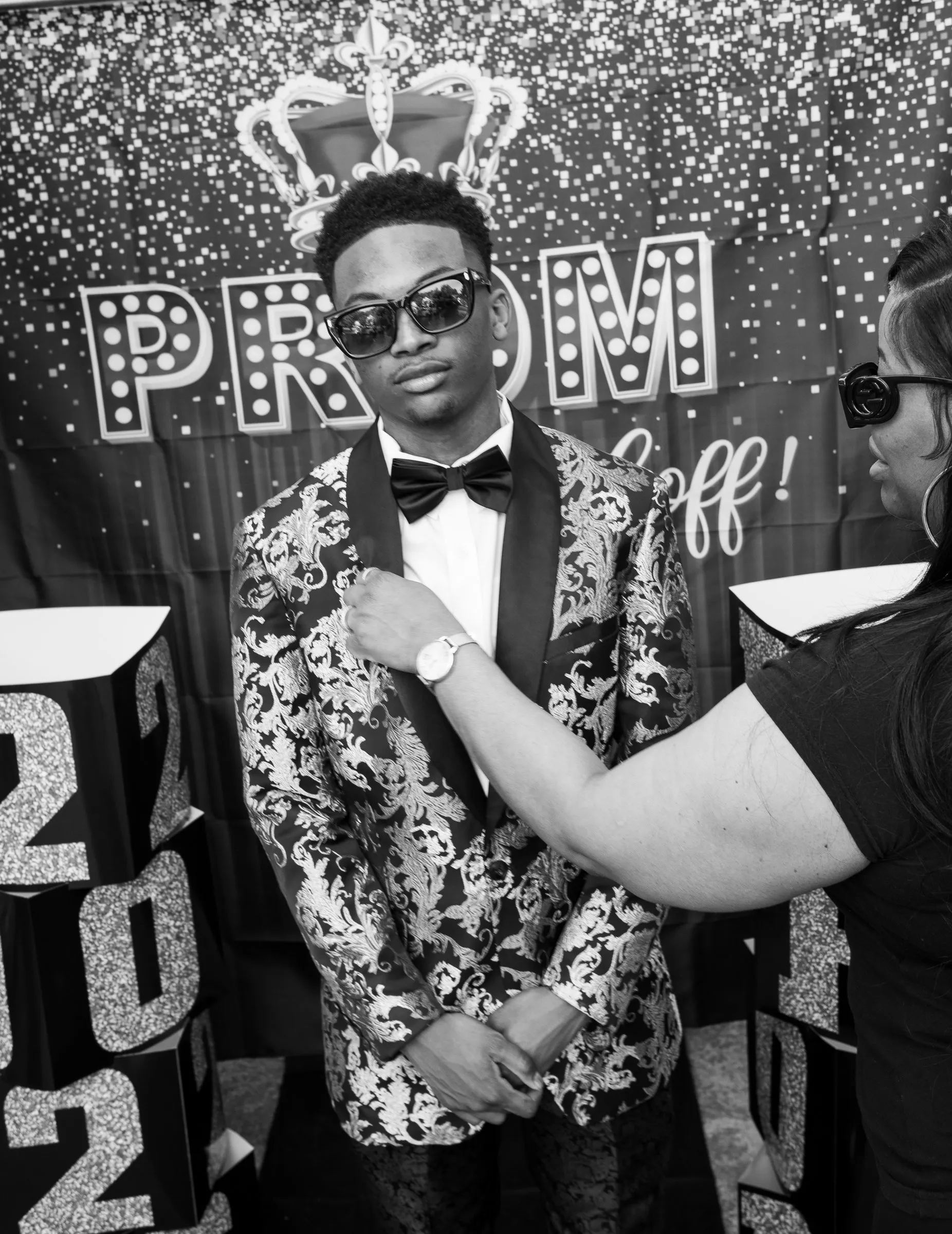 Black and white photograph of a last adjustment to his bow tie at the backdrop