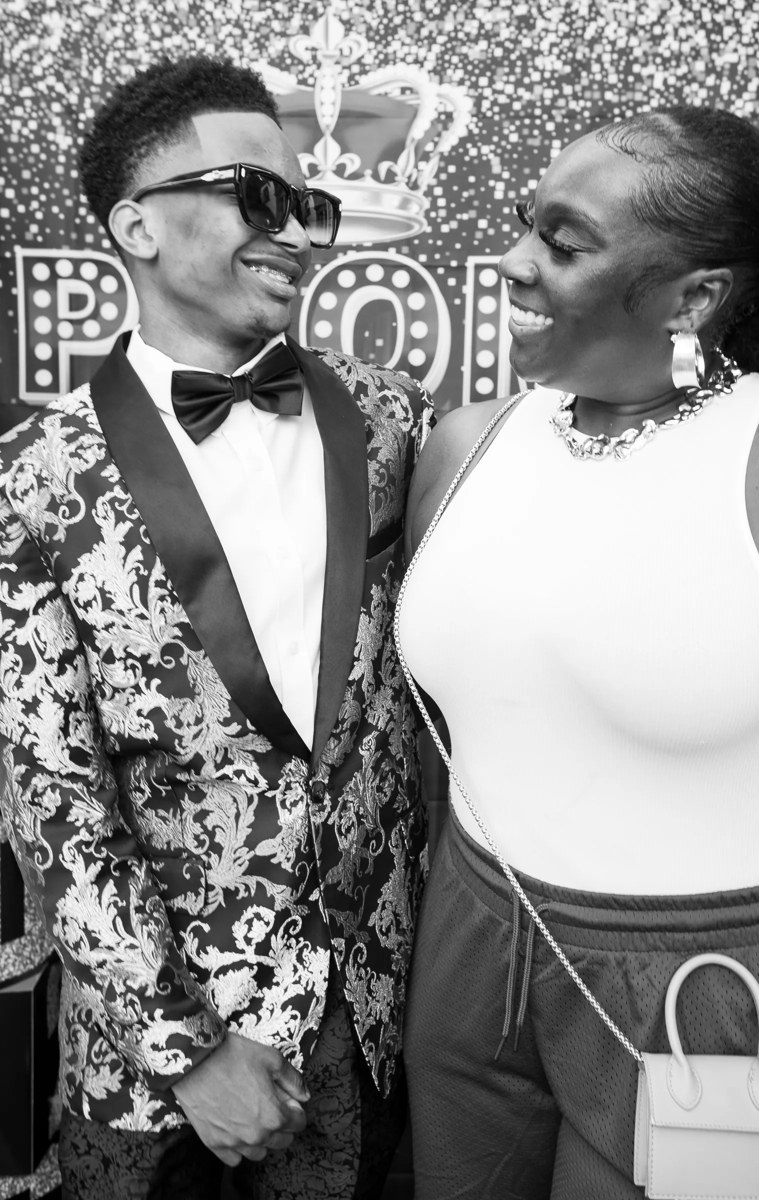 Black and white photograph of him smiling with a guest in front of the backdrop