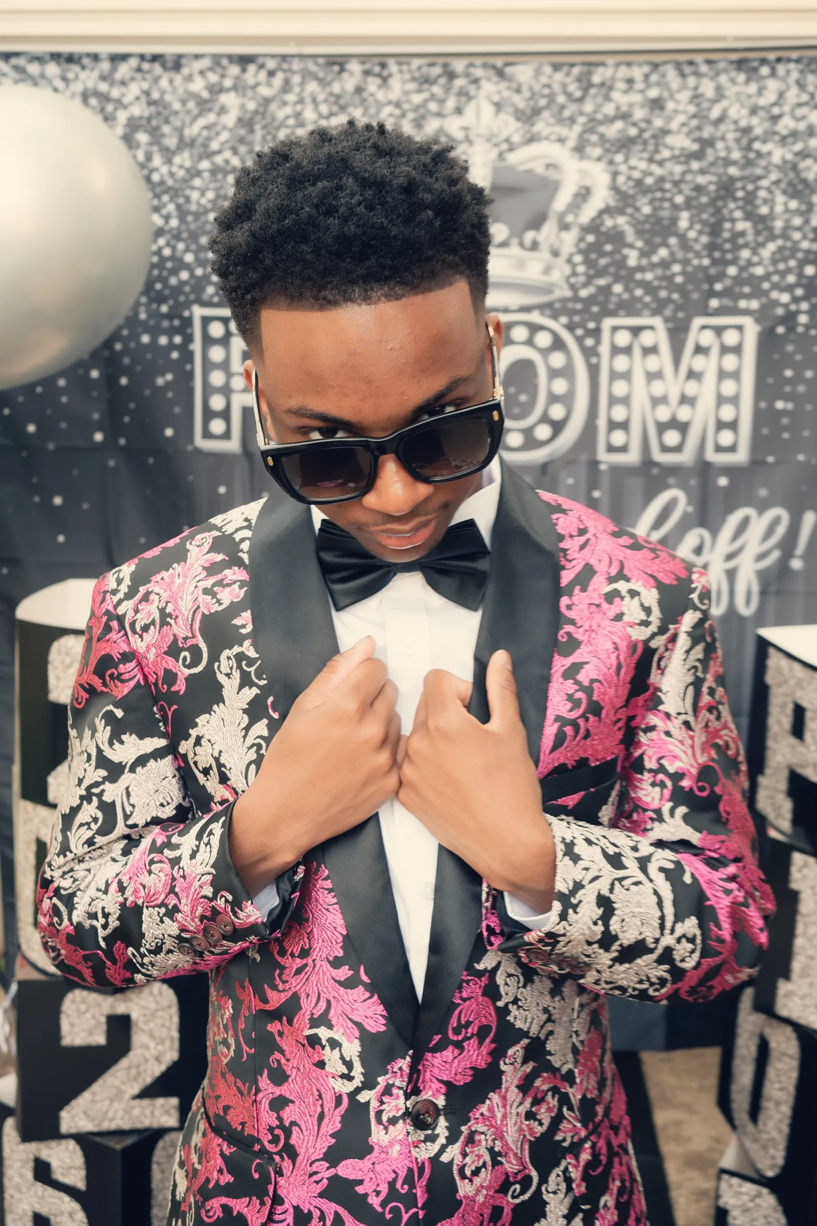 Close prom portrait gripping his lapels, sunglasses on