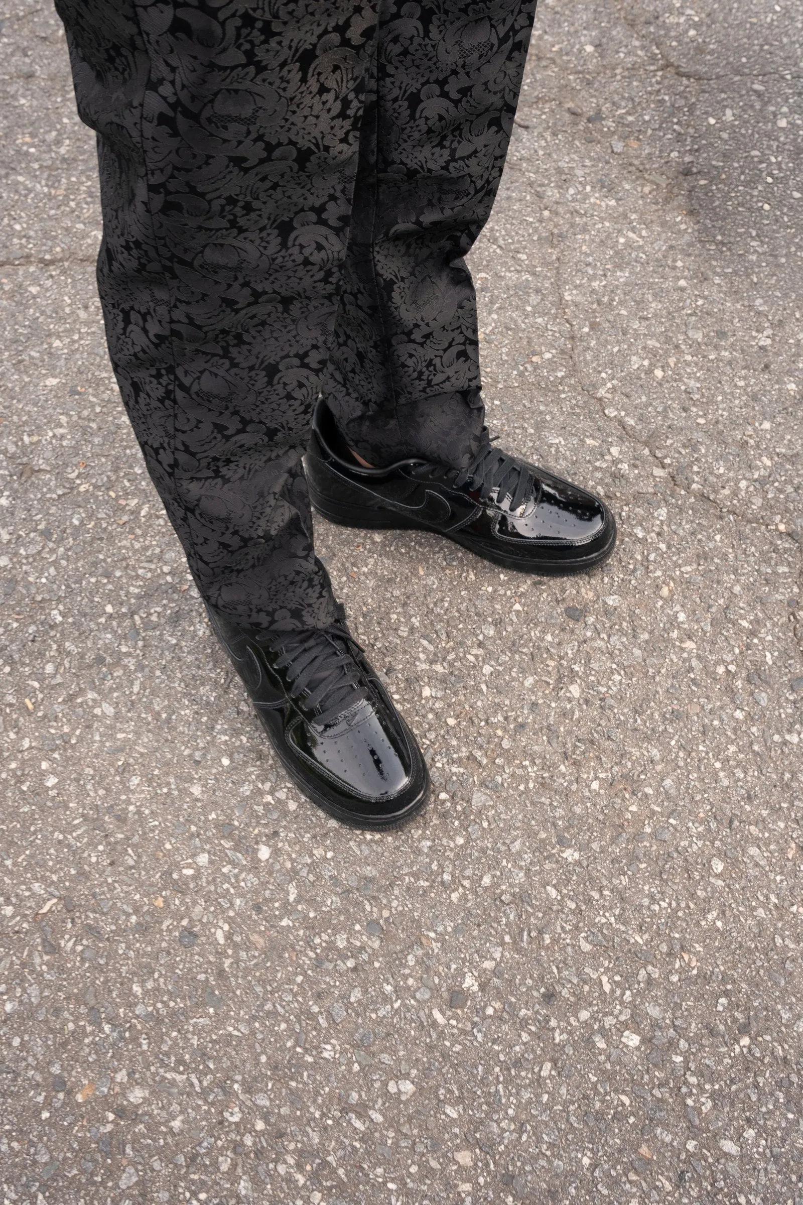Detail of his patterned black trousers and patent leather shoes