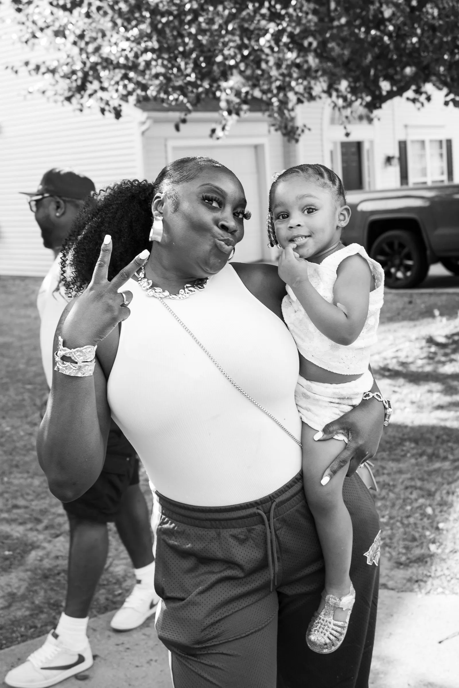 Black and white photograph of a woman holding a toddler on her hip, both posing for the camera