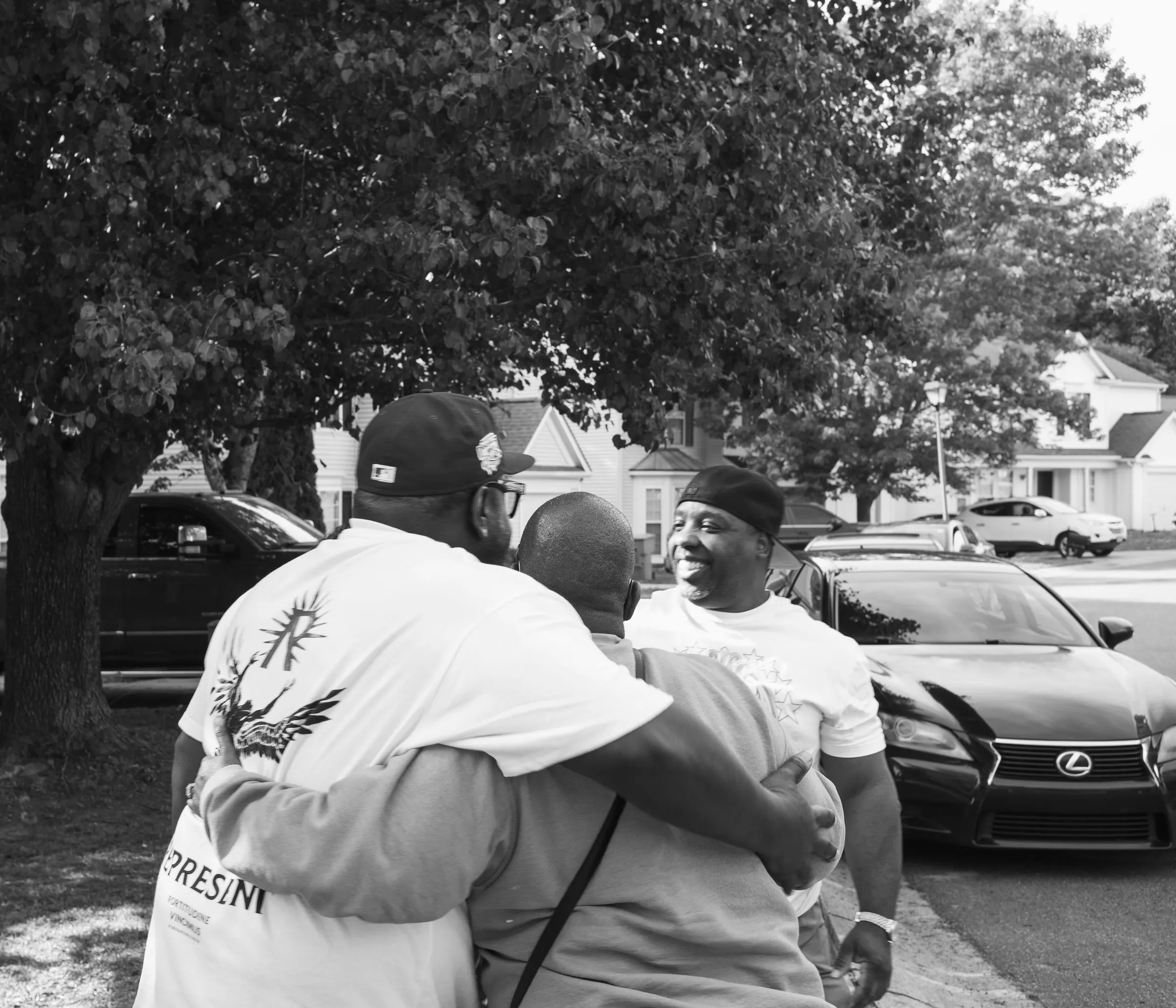 Black and white photograph of two men in a bear hug under the trees