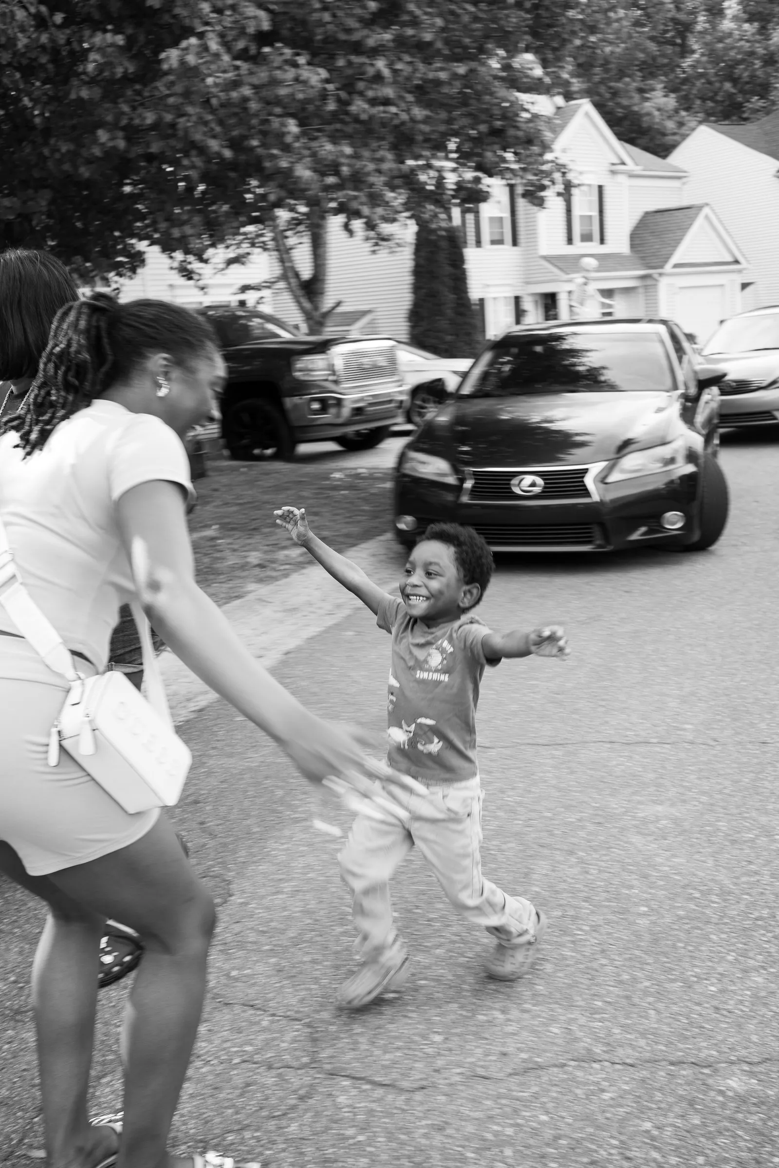 Black and white photograph of a little boy running toward a woman with open arms