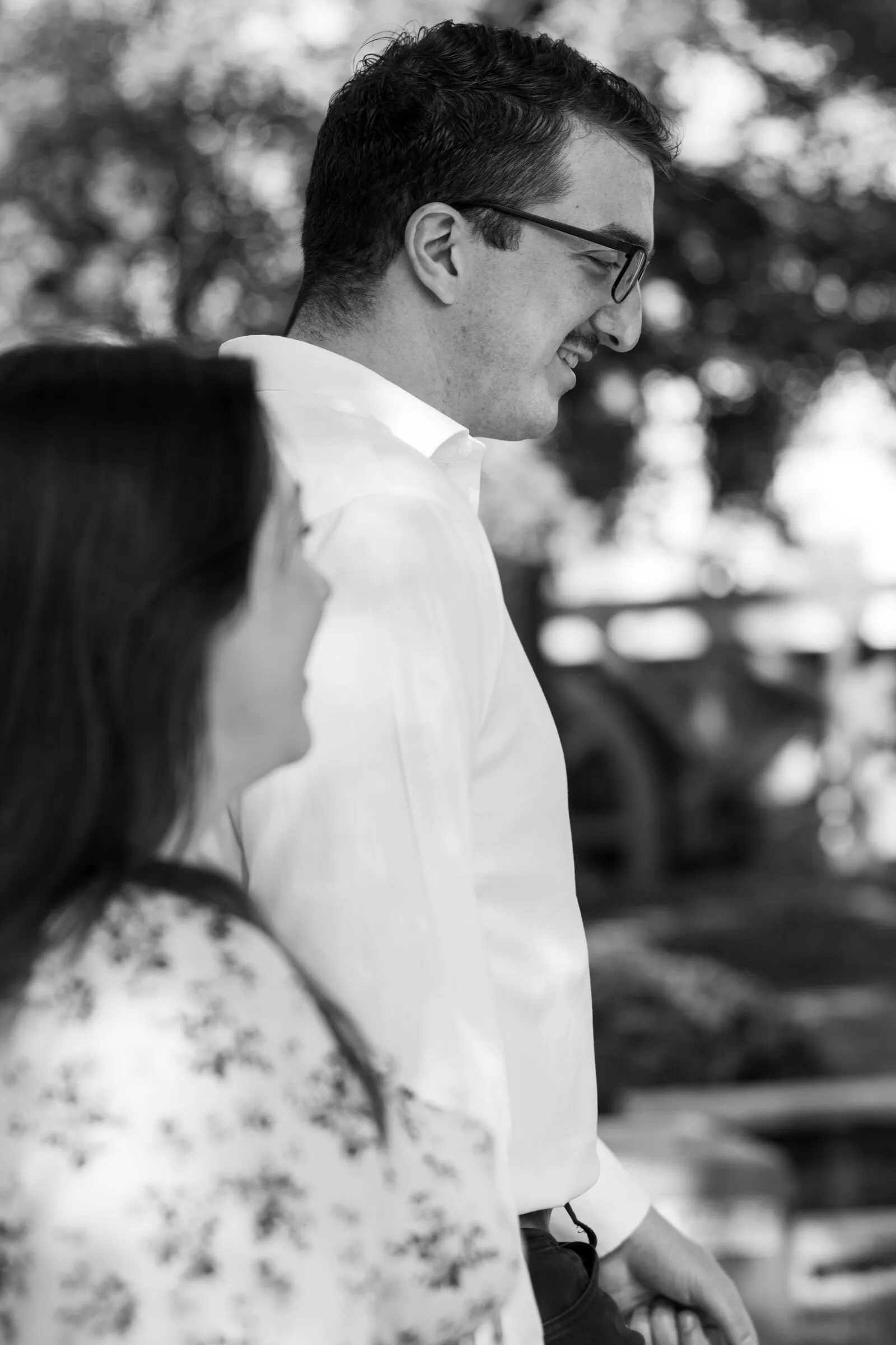Black and white frame of Spencer smiling down at Kayla as they walk