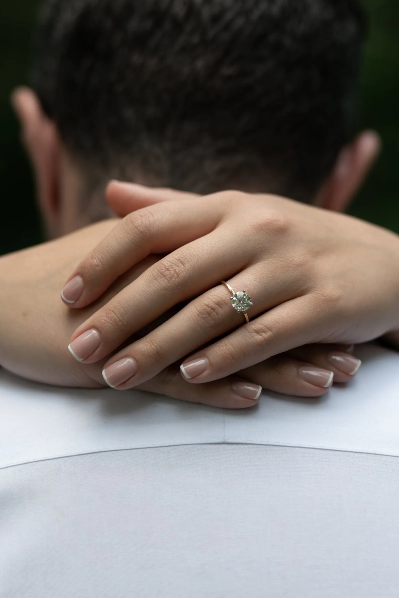 Kayla's hands folded over Spencer's shoulder, her engagement ring catching the light