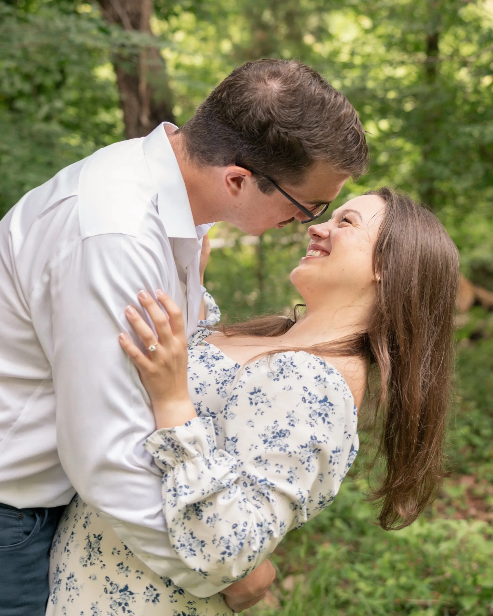 Spencer leaning in as Kayla smiles up at him in the woods, her hand on his shoulder