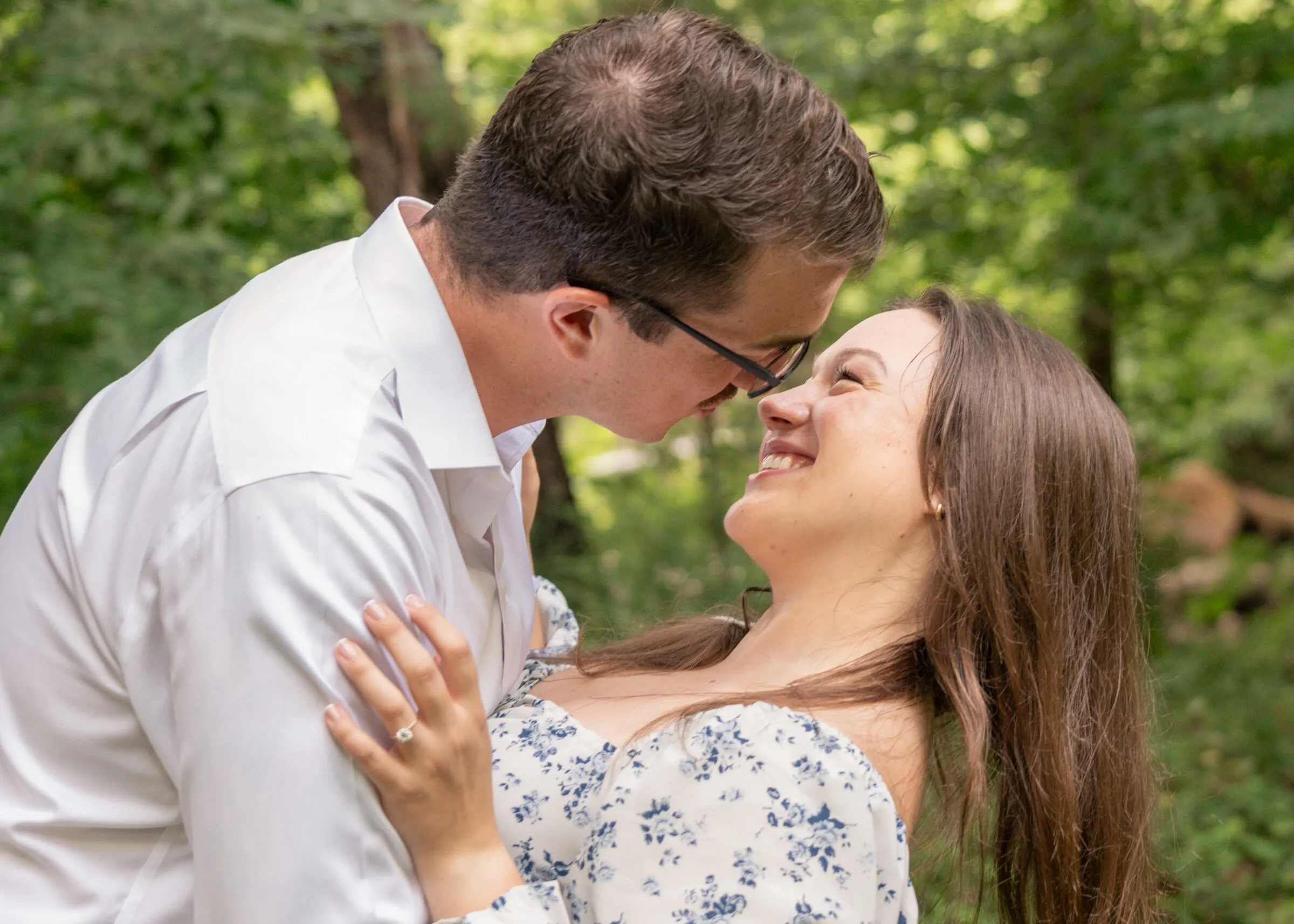 Spencer and Kayla nose to nose and smiling in a green woodland clearing