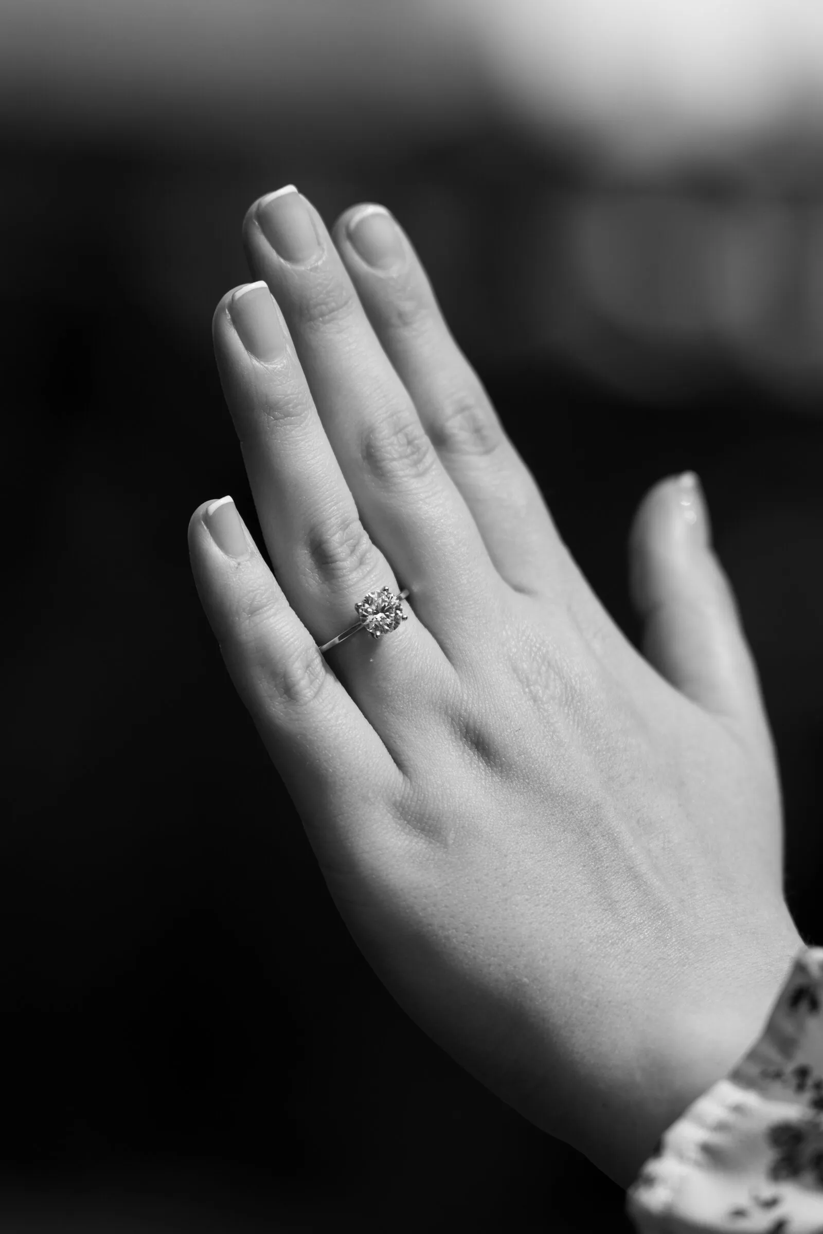 Black and white detail of Kayla holding up her hand to show her engagement ring