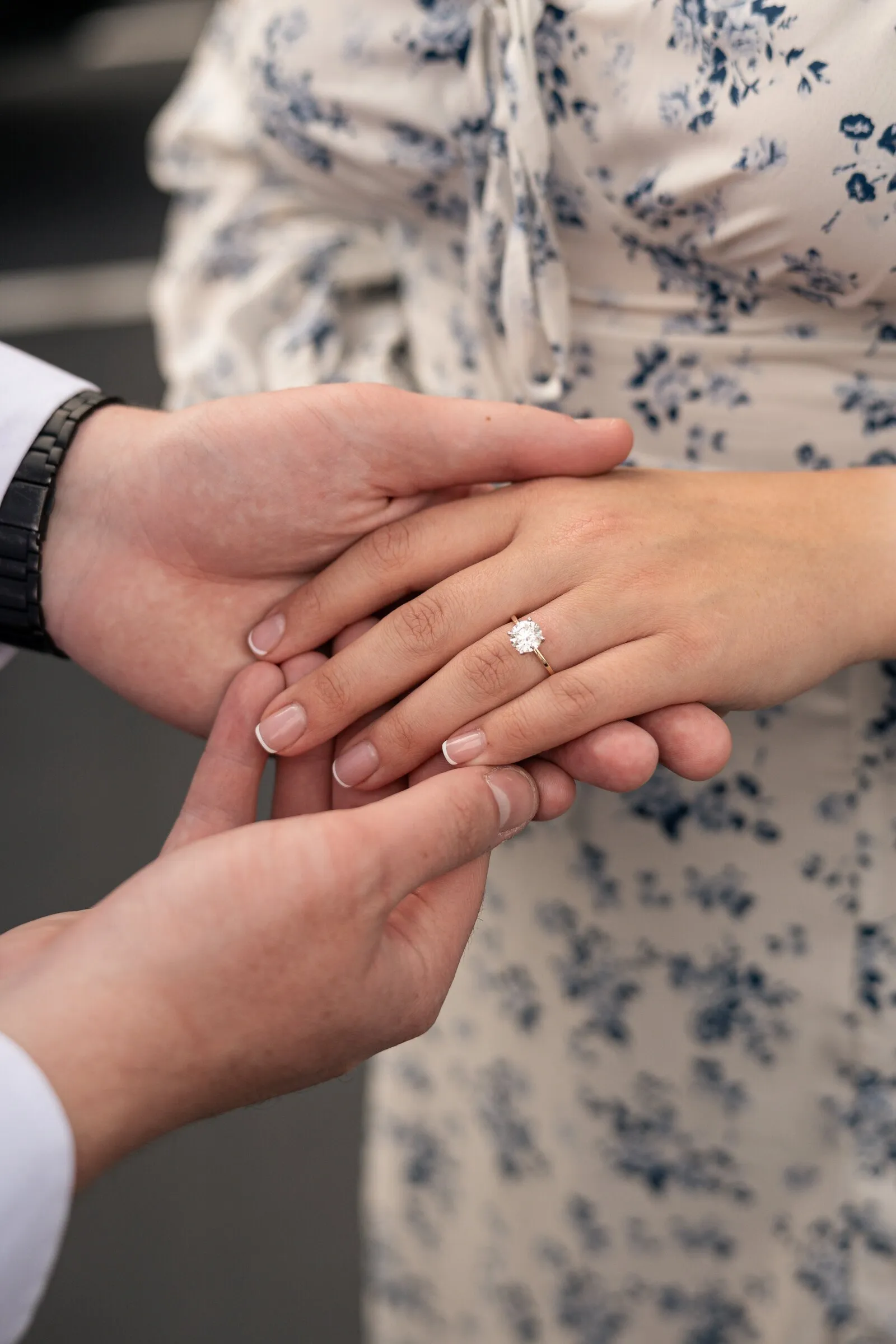 Spencer holding Kayla's hand between both of his, her engagement ring in the center
