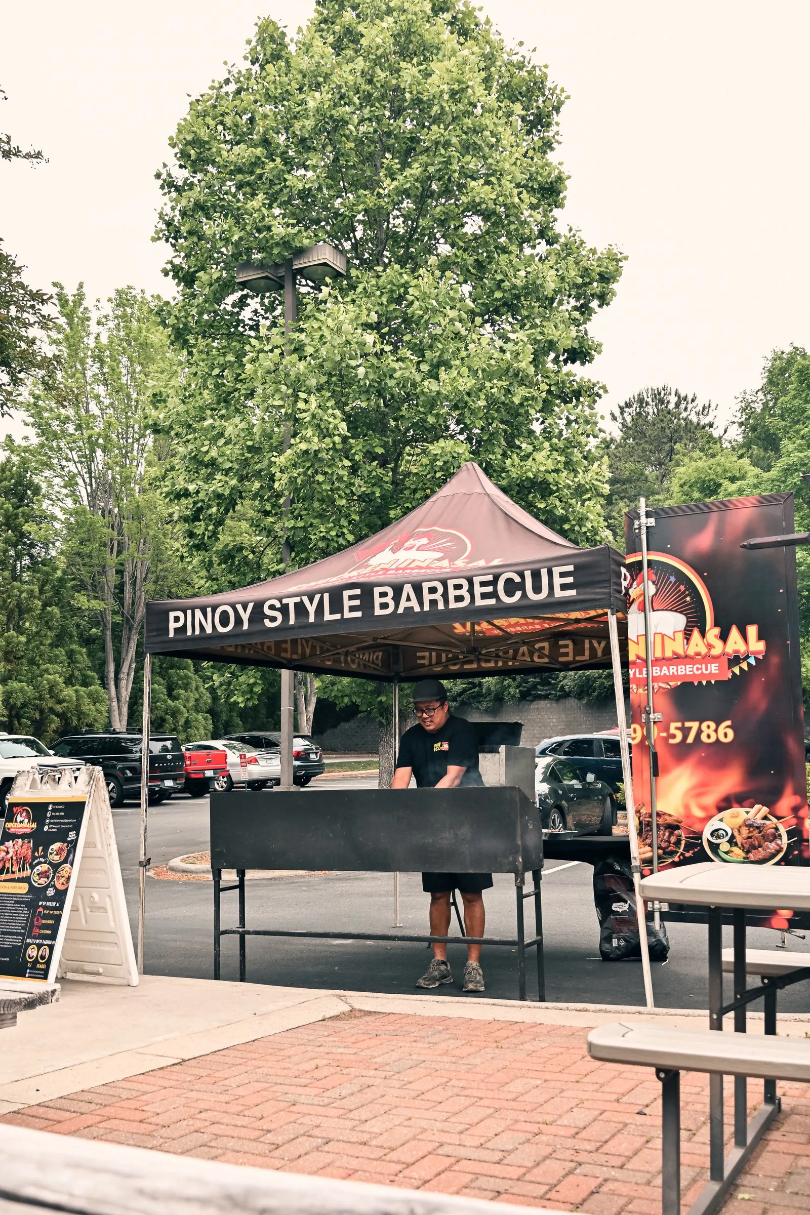 The Pinoy Style Barbecue tent and grill across the brick patio and picnic tables