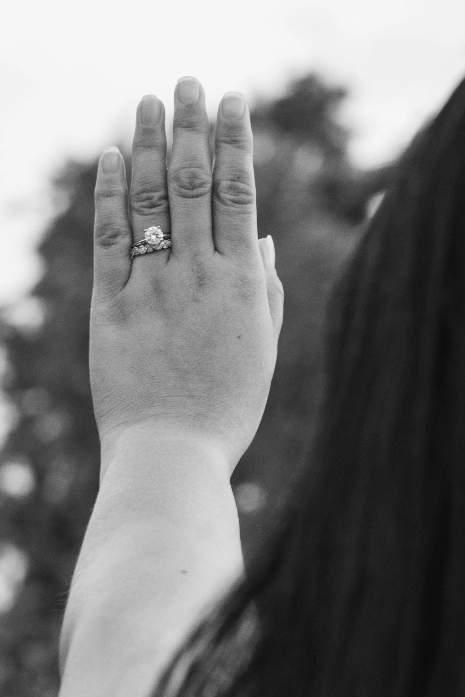 Black and white photograph of Winnie raising her left hand to show her engagement ring and wedding band