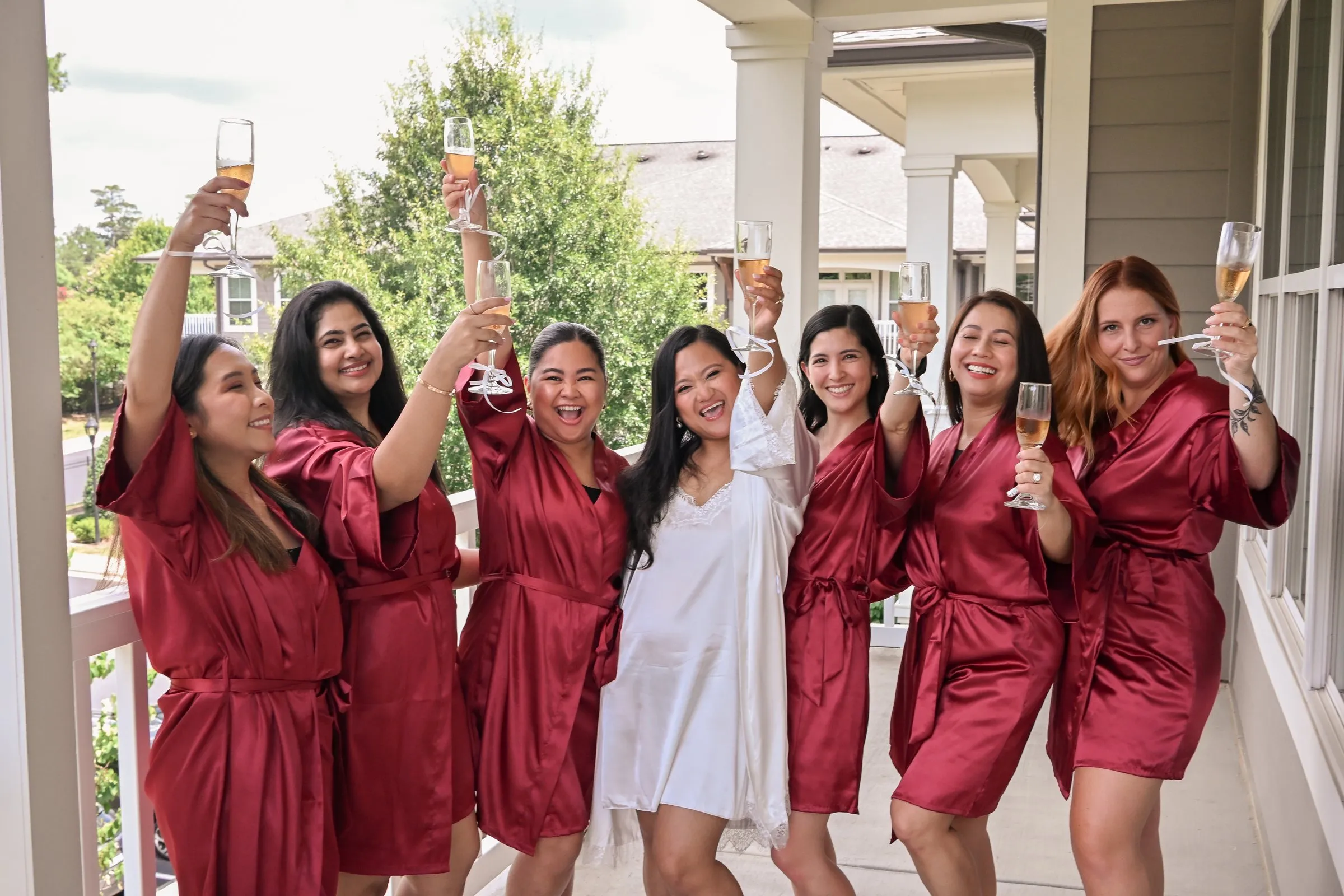 Winnie and her bridesmaids raising their champagne glasses high on the balcony