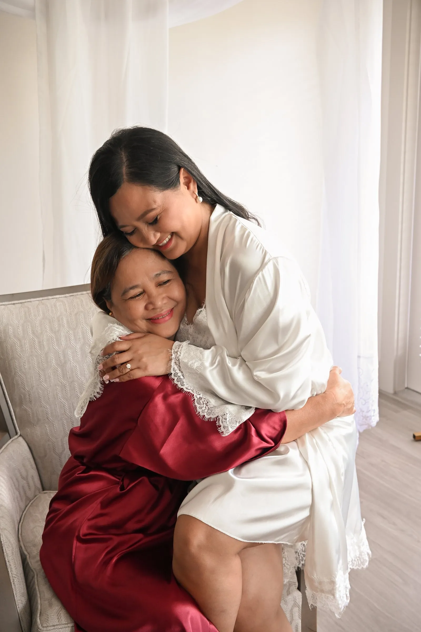 Winnie in her white robe hugging her mom on her wedding morning in Charlotte, NC